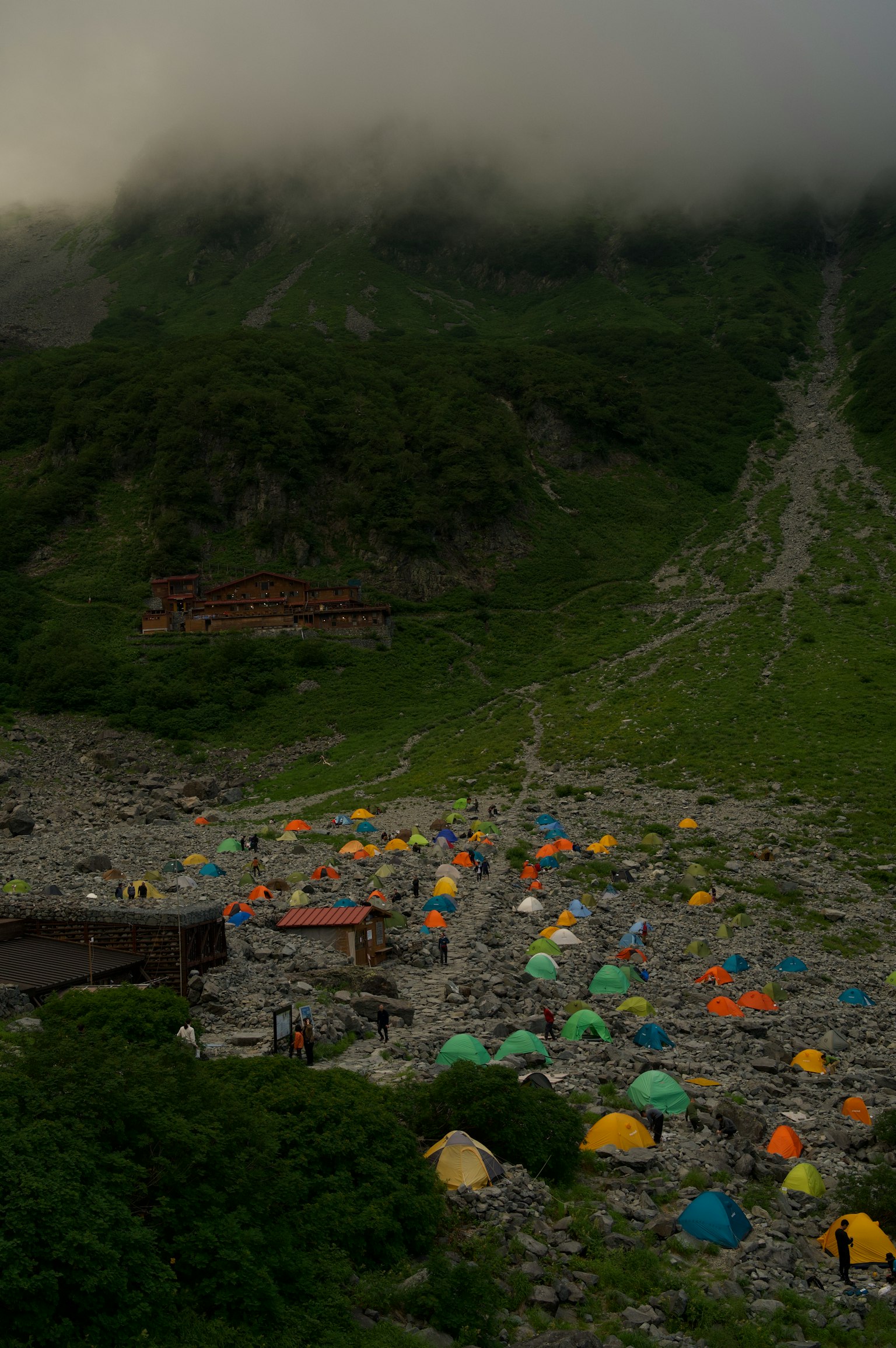Camp site in the mountains shrouded in fog colorful tents scattered across the landscape