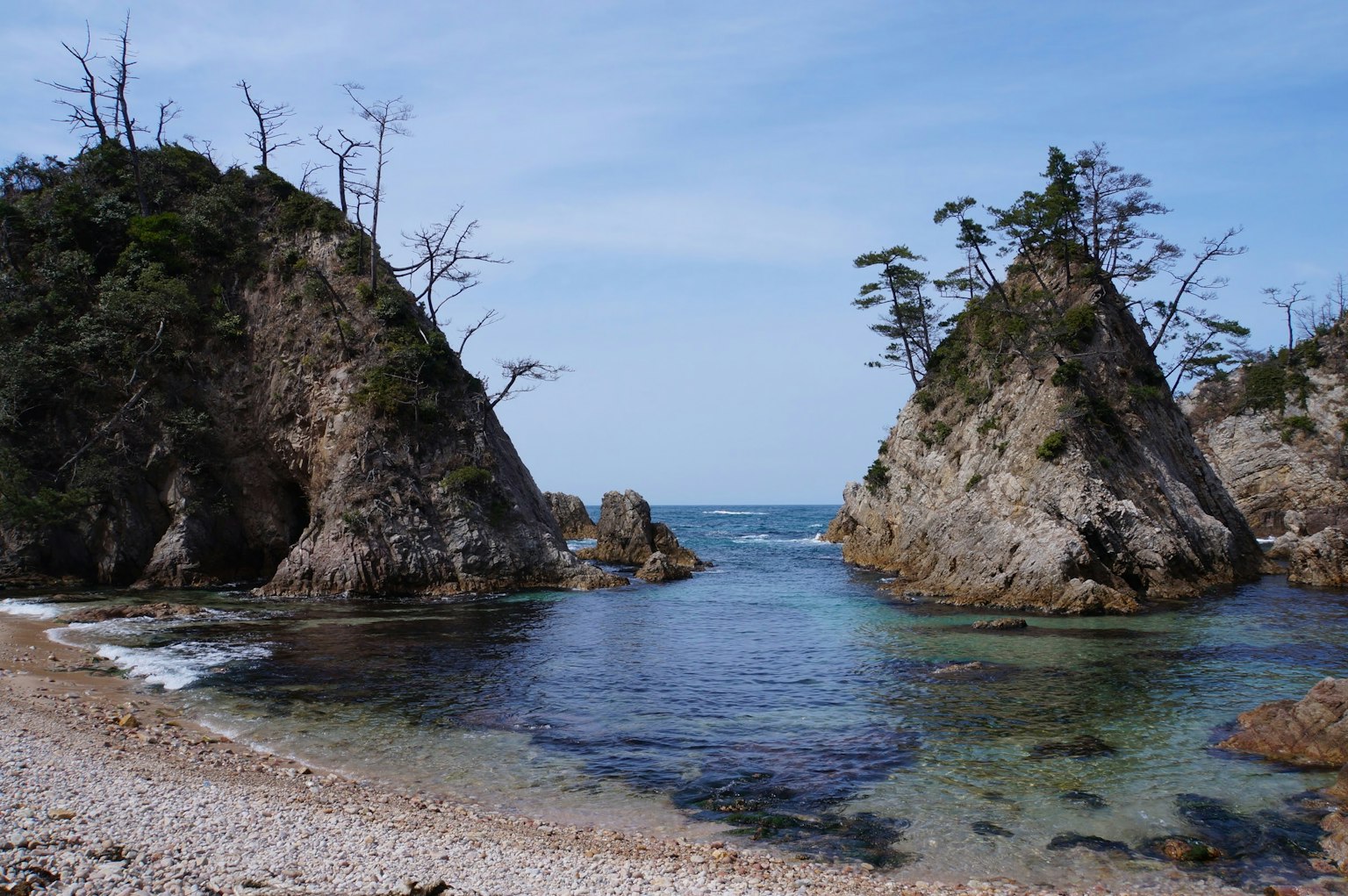 Due formazioni rocciose circondate da acqua blu e una spiaggia sabbiosa