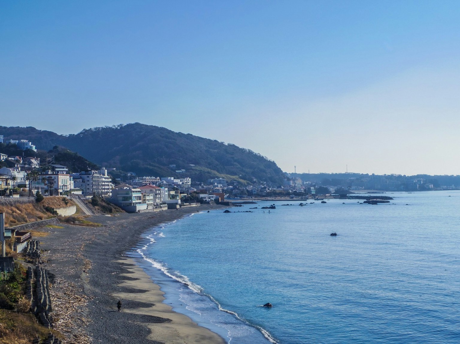 Vue panoramique d'une côte avec une mer calme et un ciel bleu, mettant en valeur une ville balnéaire