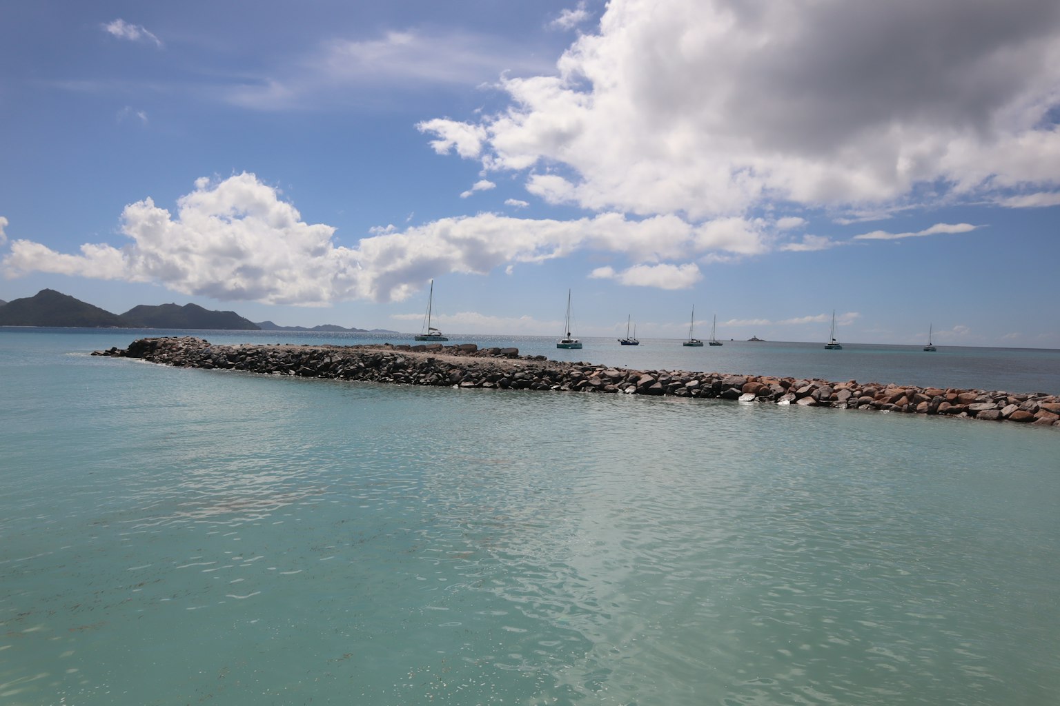 Pemandangan laut tenang dan langit biru Dermaga batu yang menjulur ke dalam air