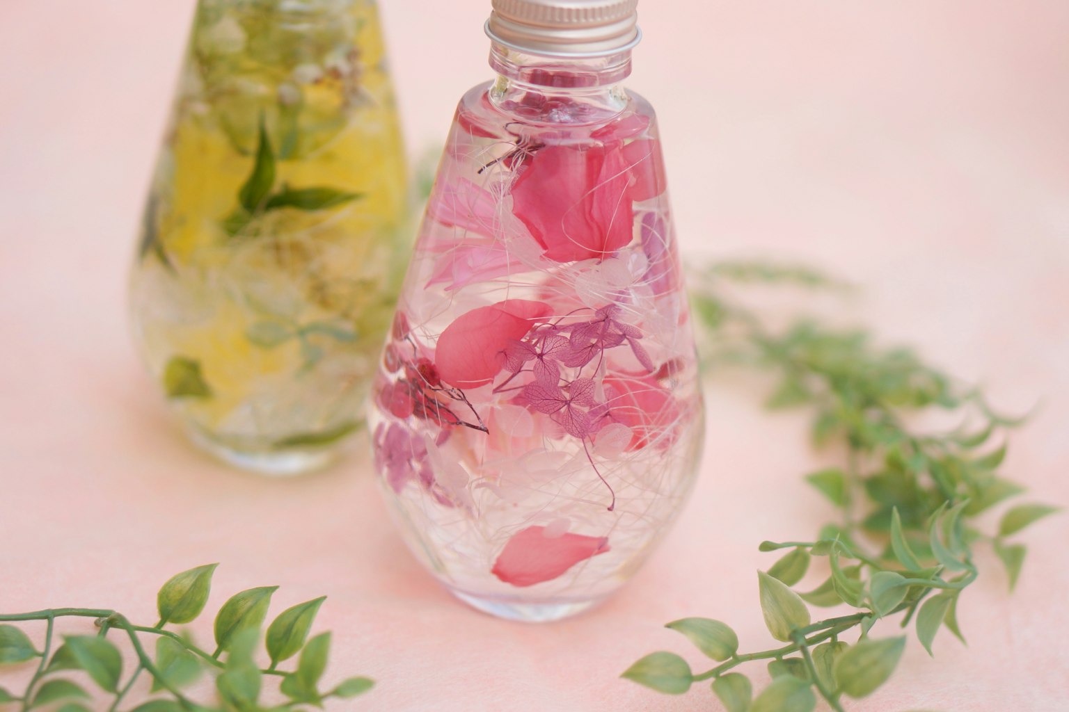 Transparente Flasche mit rosa Rosenblättern und grünen Blättern Dekoration