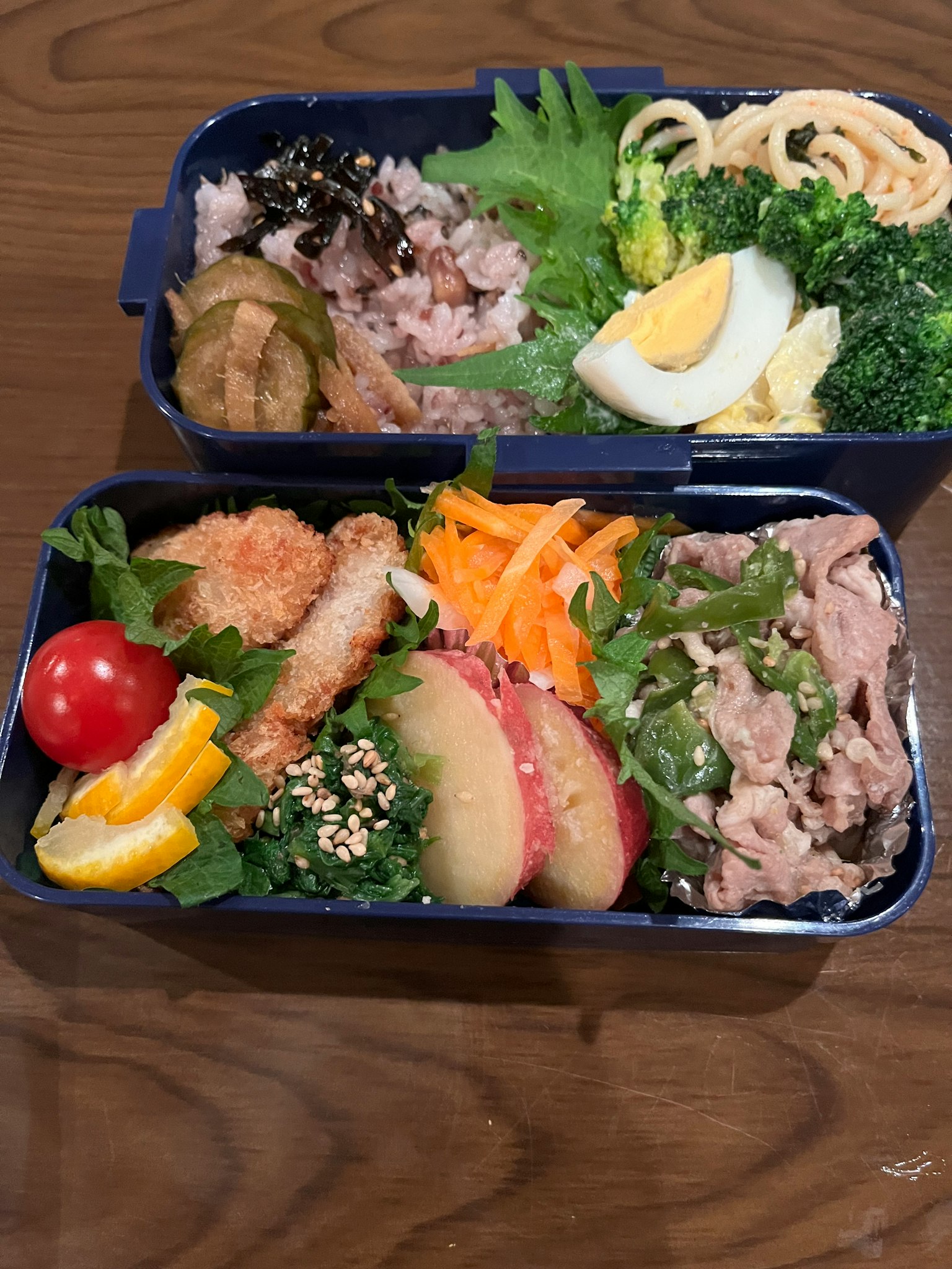 กล่องเบนโตะอร่อยที่มีบรอกโคลีไข่ต้มเทมปุระกุ้งมะเขือเทศเชอร์รีและผลไม้