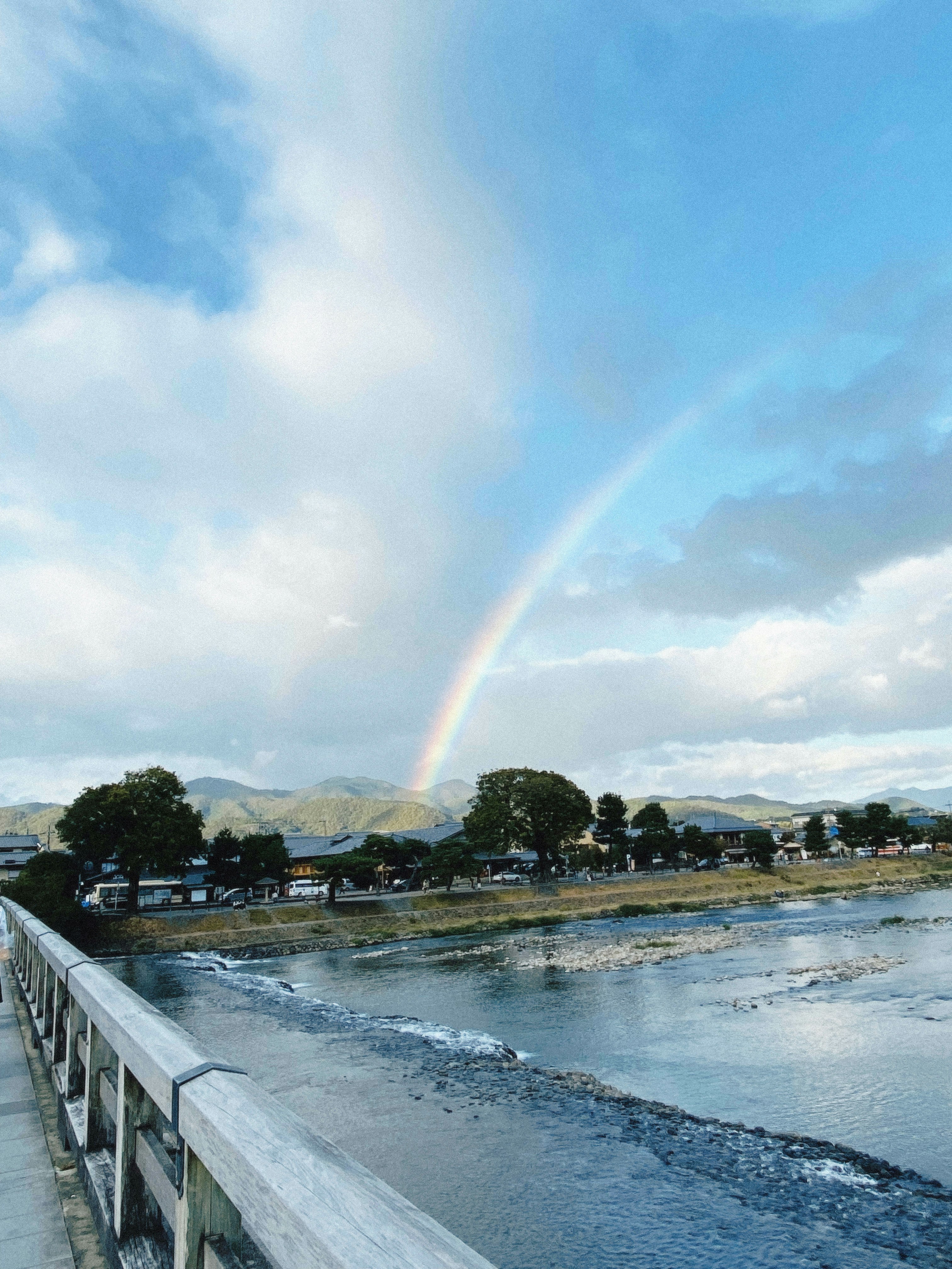 川沿いの遊歩道と空にかかる虹
