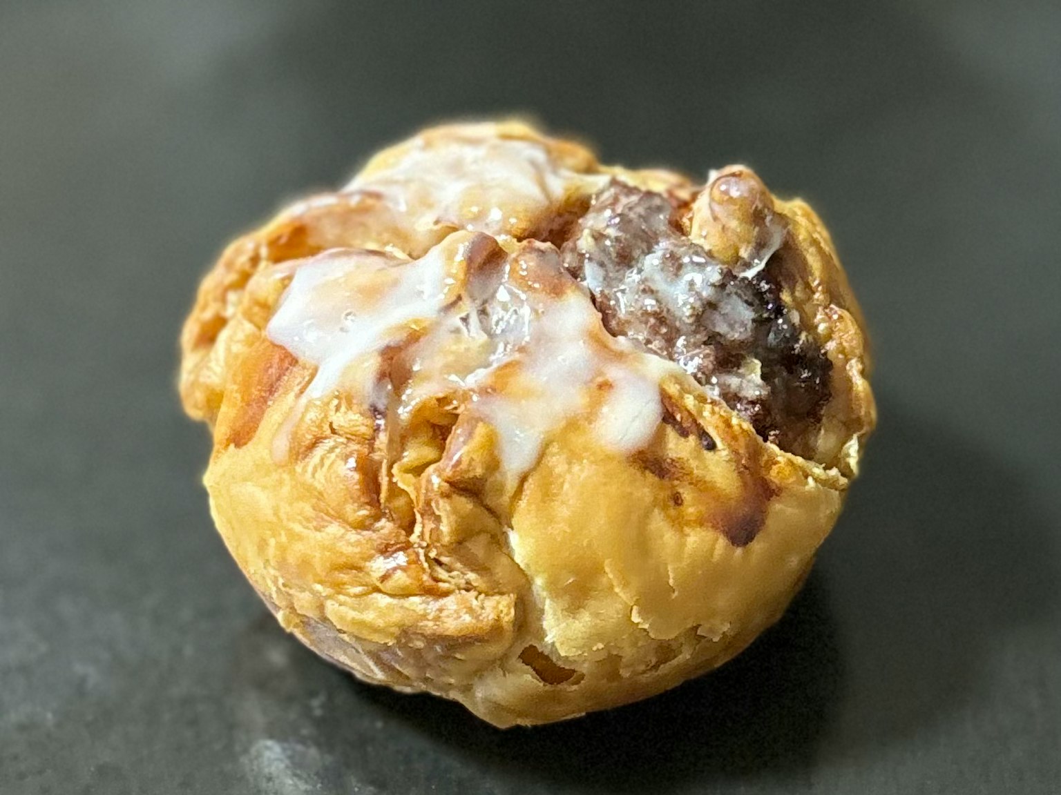 Close-up of a pastry with caramel and cream topping on a black plate