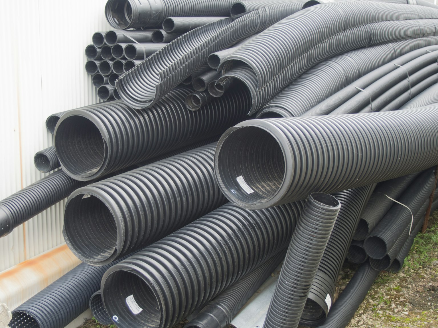 Une collection de tuyaux noirs empilés dans un environnement industriel