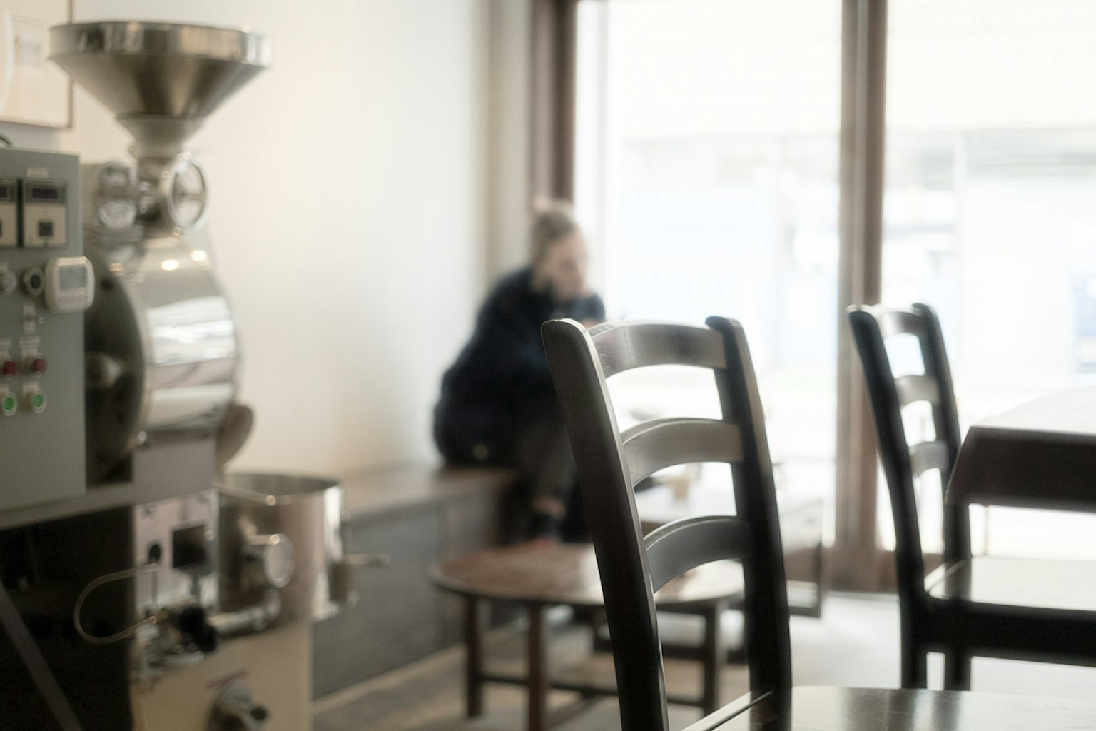 Interior de una cafetería con sillas y una máquina de tostar café