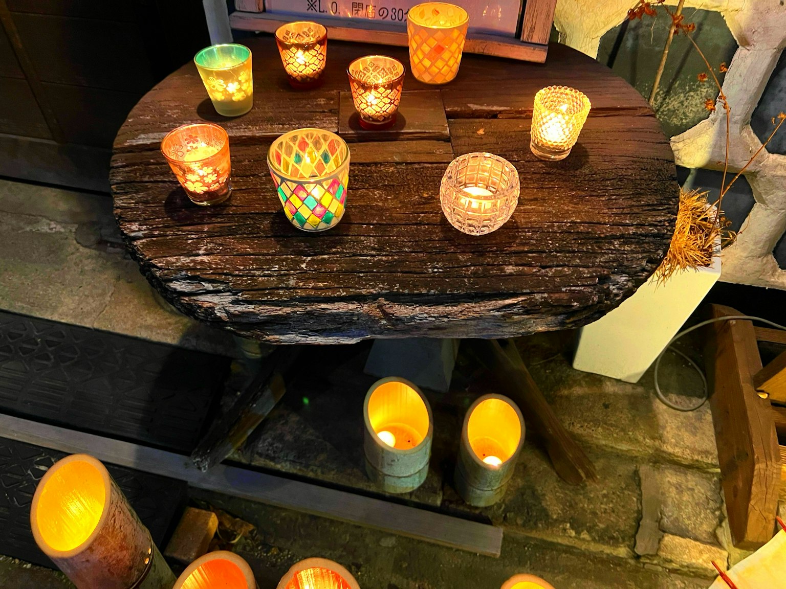 Varios portavelas decorados y velas brillantes dispuestos sobre una mesa de madera