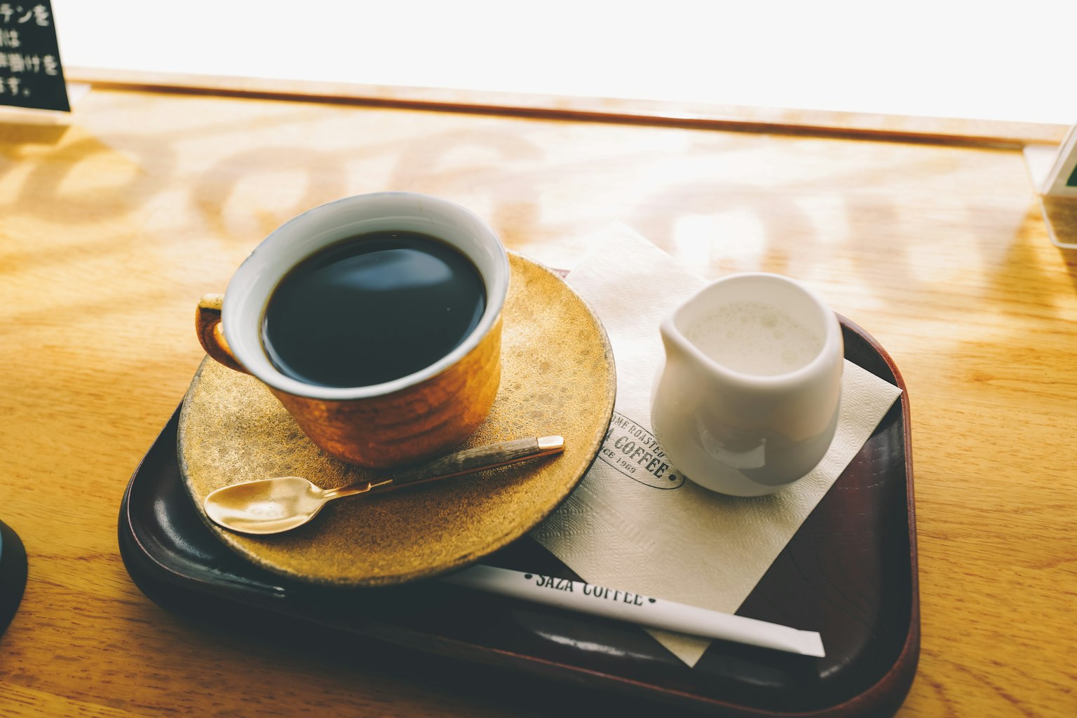 Une tasse de café et de la crème sur un plateau avec une cuillère et une serviette