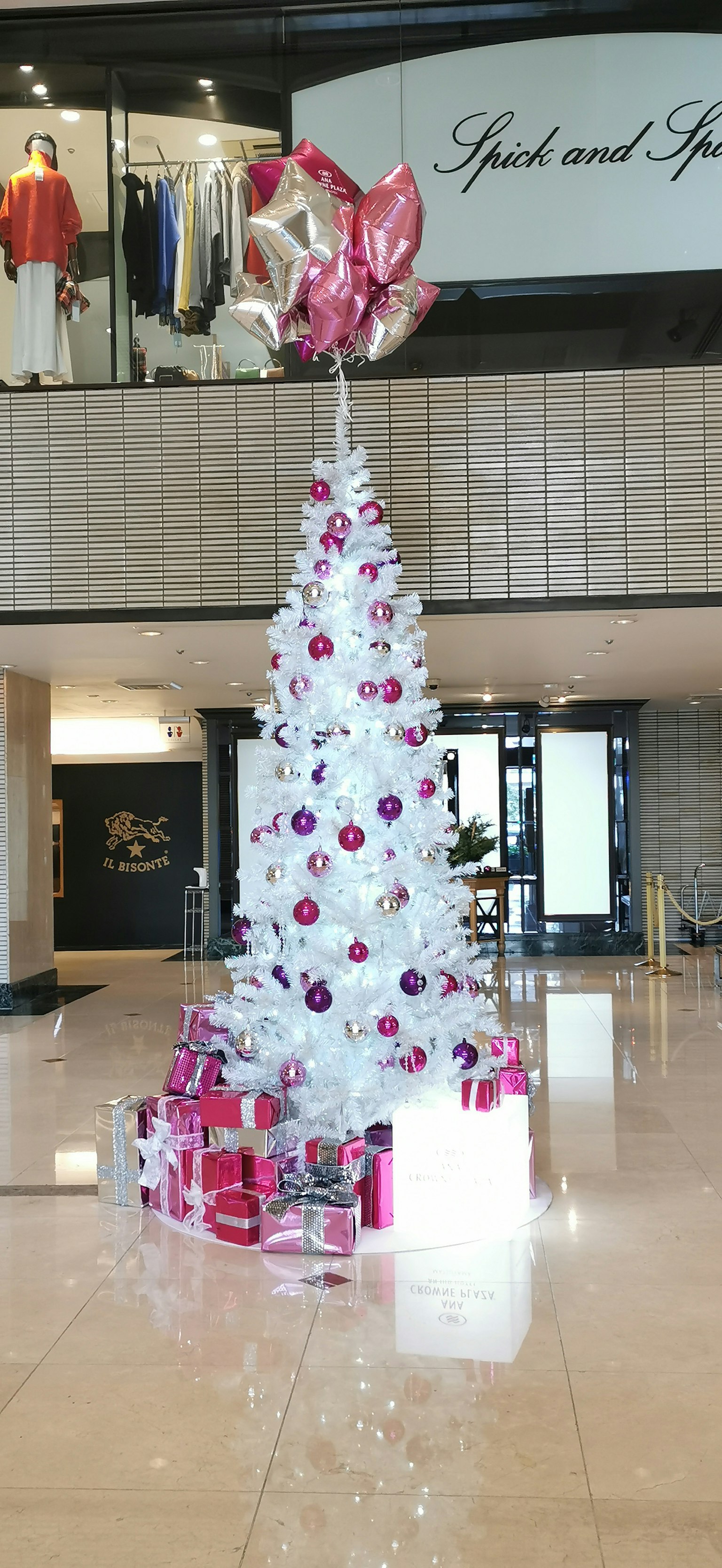 Albero di Natale bianco decorato con ornamenti rosa e viola circondato da scatole regalo