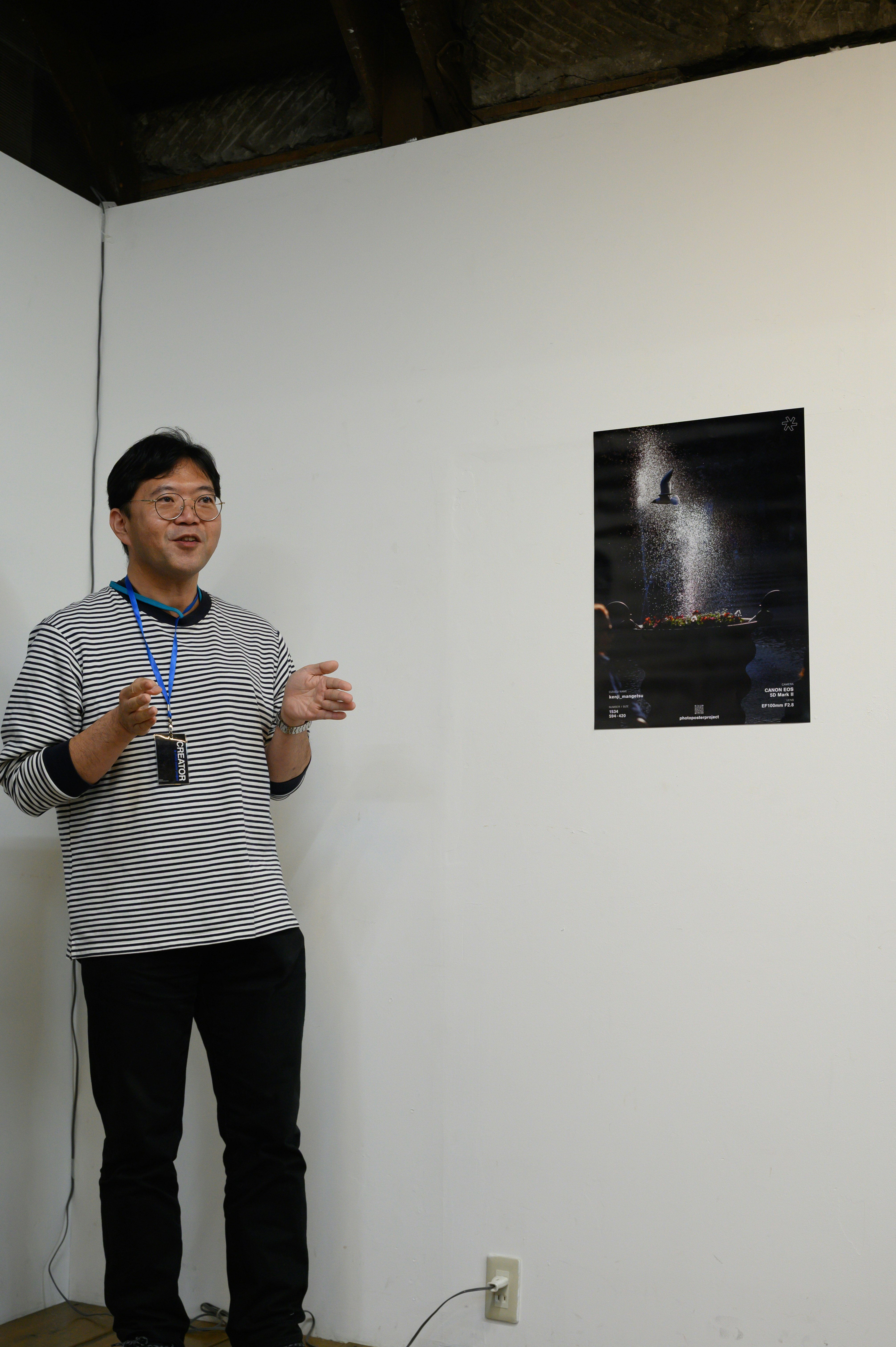 白い展示スペースでスーツケースのような展示物の前に立つ男性