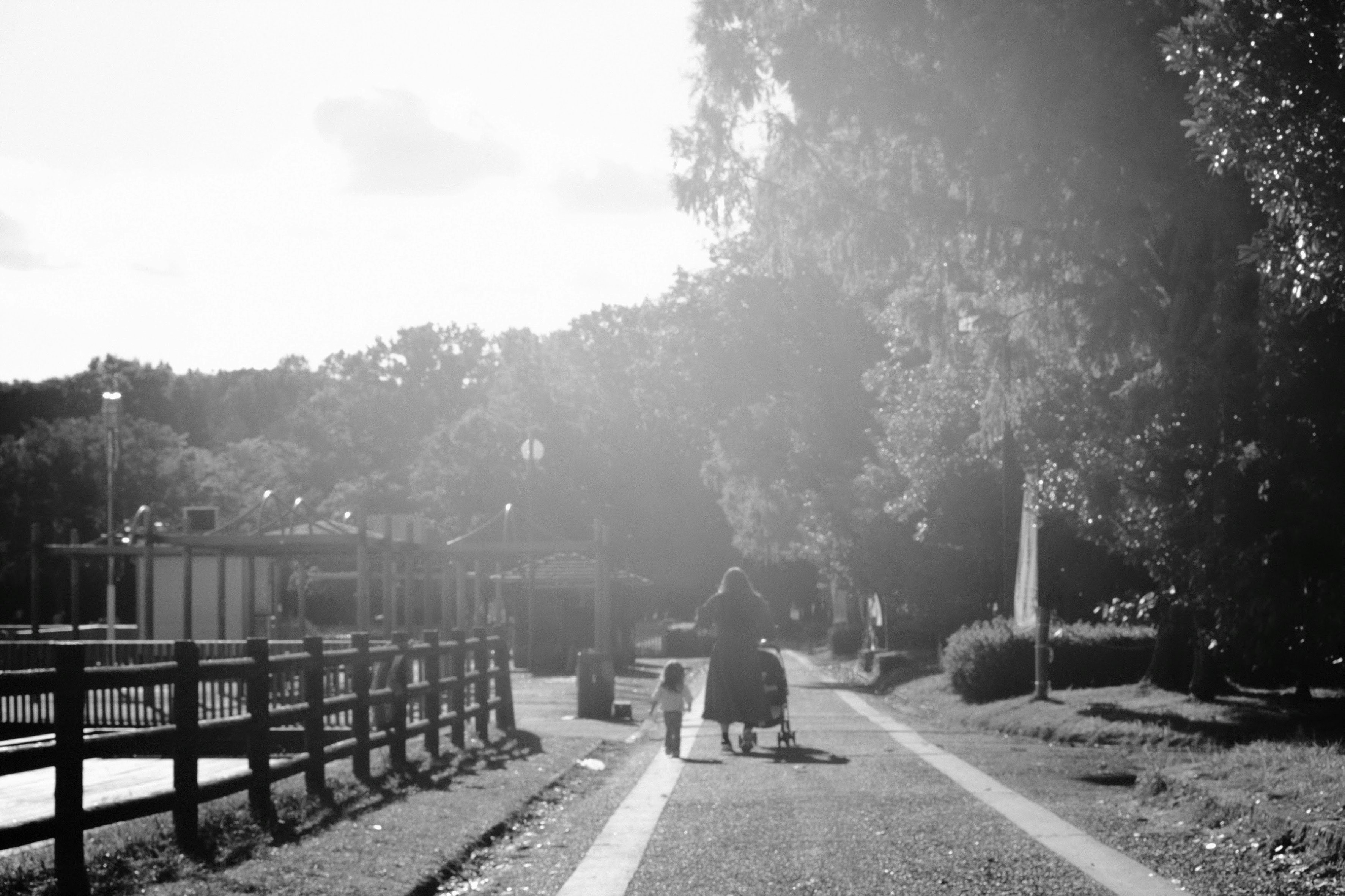 genitore e bambino che camminano lungo un sentiero di parco urbano con aloni