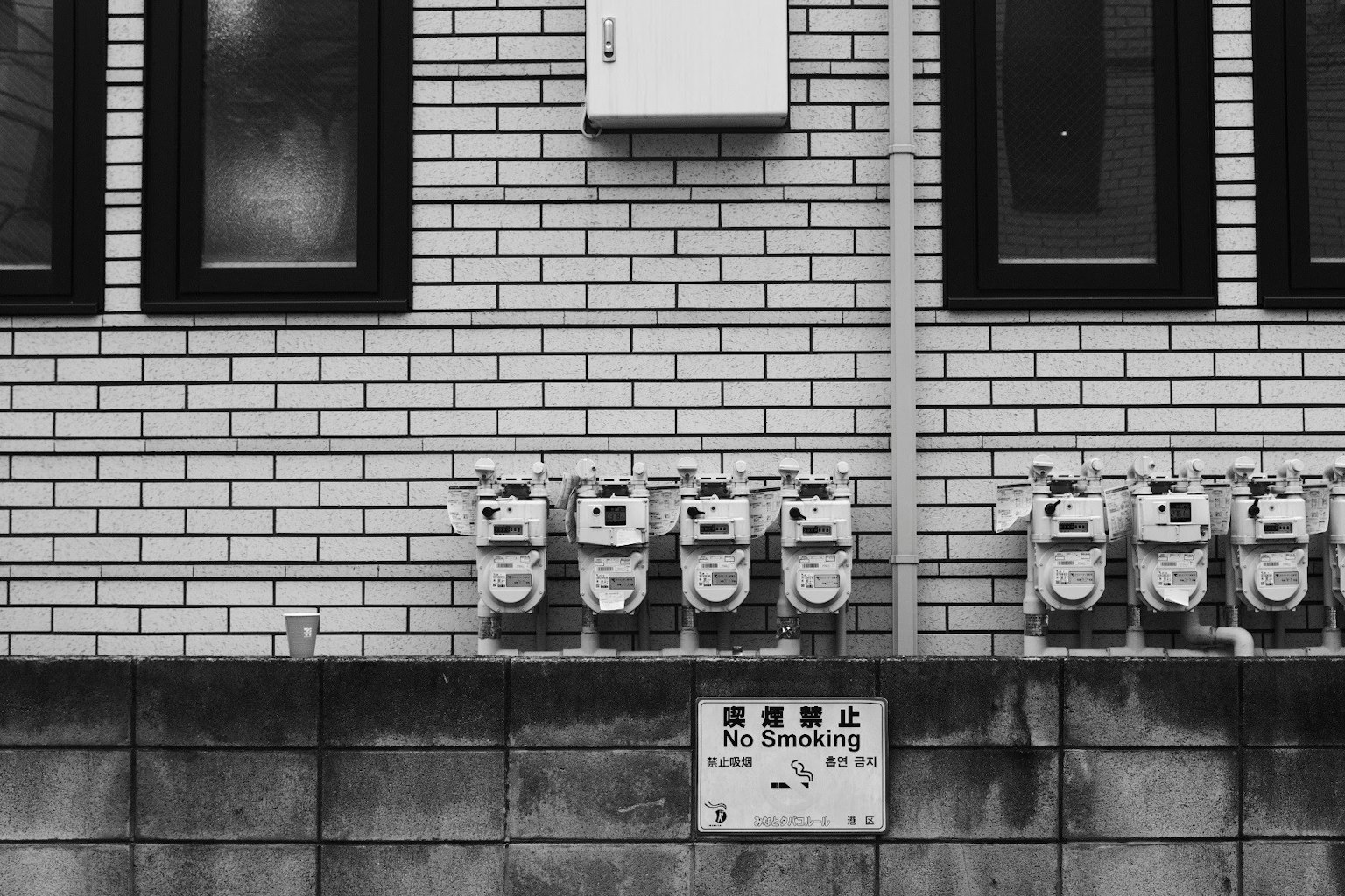 Varios medidores de gas montados en una pared de ladrillo con ventanas en blanco y negro