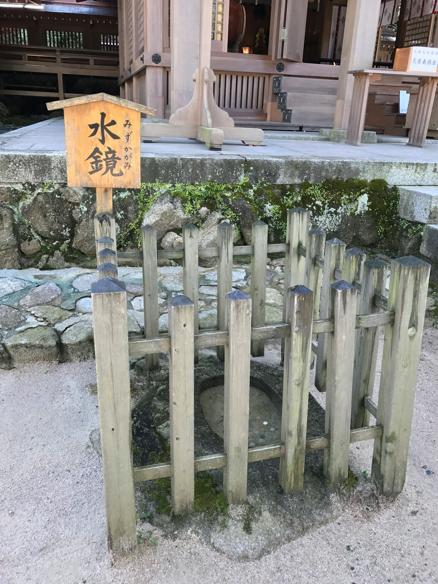 Bak air tradisional Jepang dengan pagar kayu dan papan nama