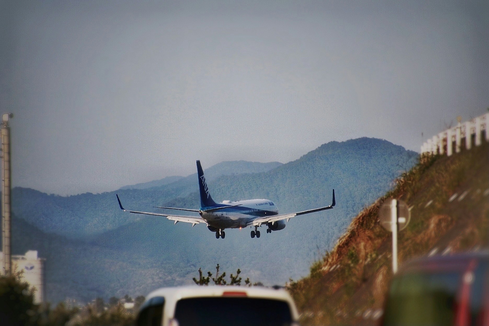 山あいの空港付近で着陸する飛行機と走行中の車