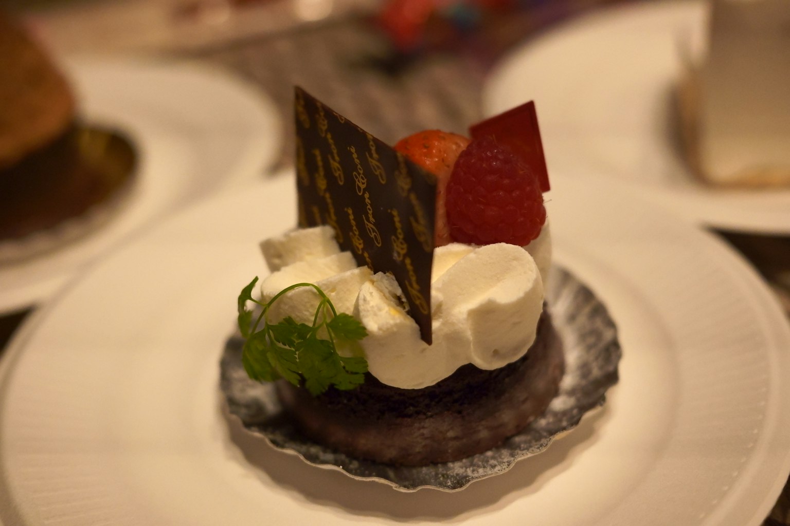 Kue coklat dihiasi dengan krim kocok dan elemen dekoratif di atas piring dessert