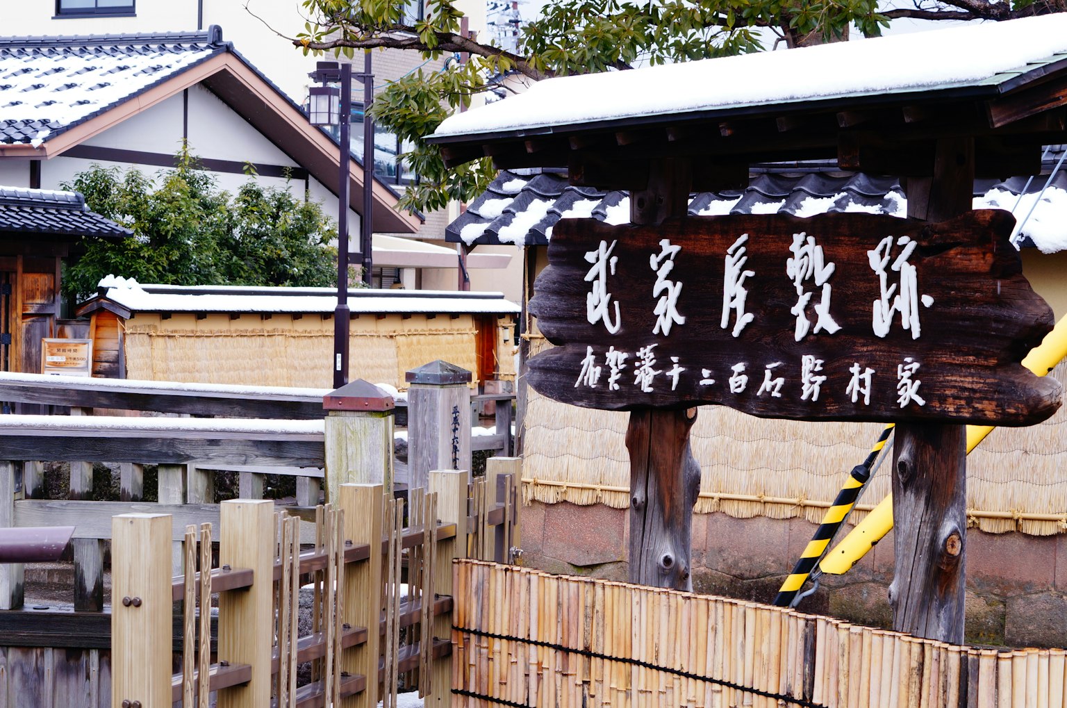Papan kayu di depan bangunan tradisional Jepang yang tertutup salju