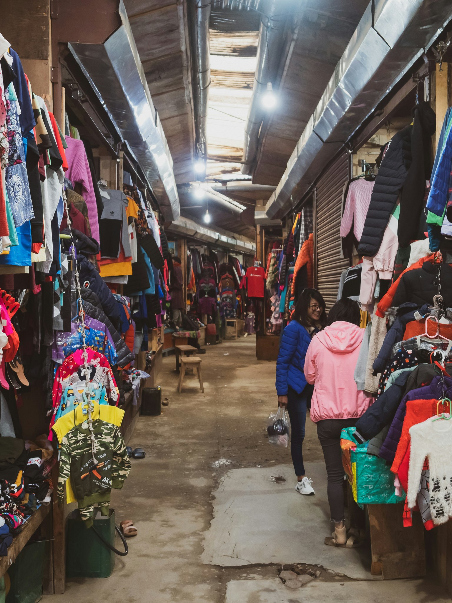 Corridoio di mercato stretto fiancheggiato da abbigliamento colorato in esposizione