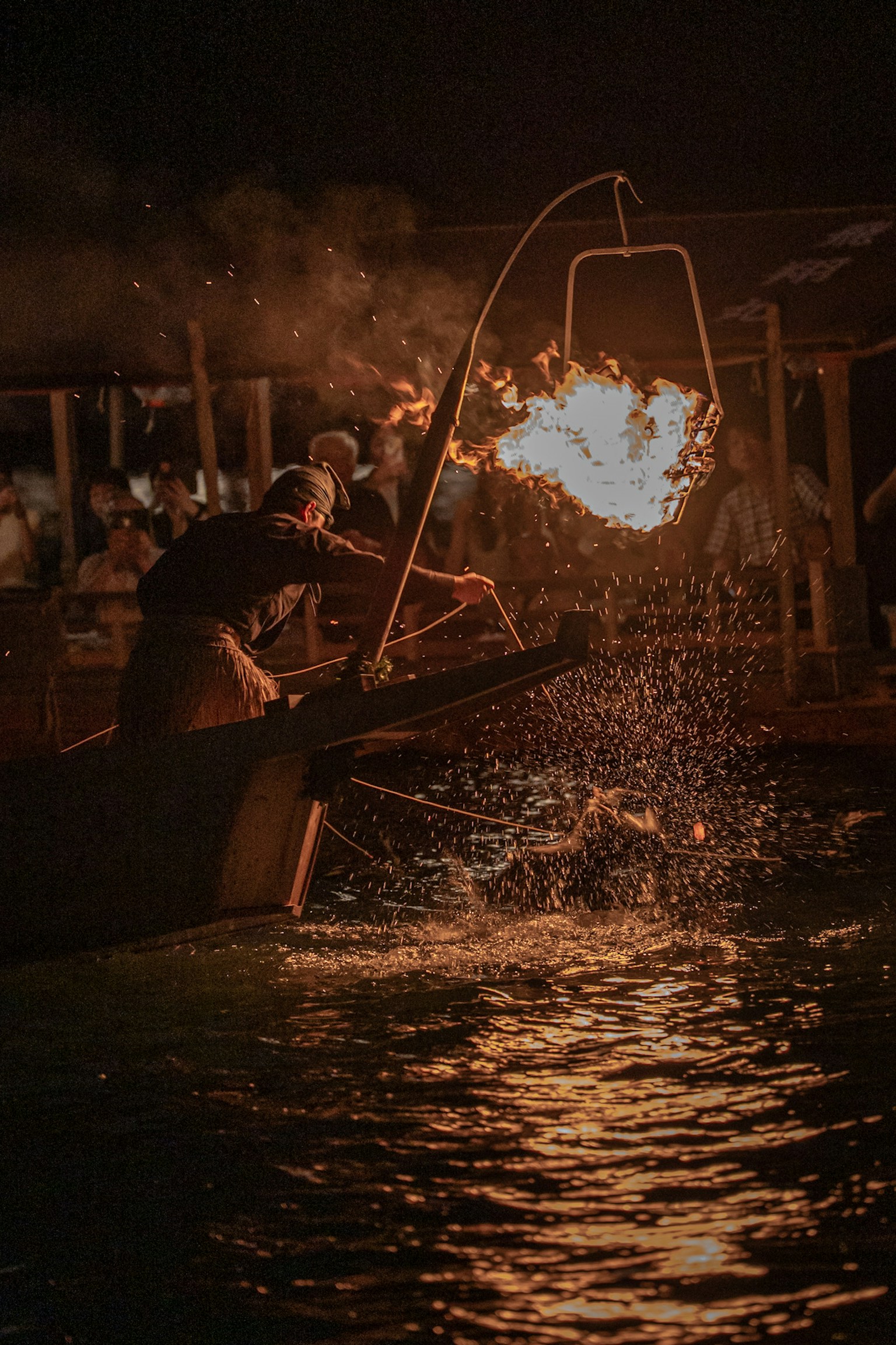 Nelayan menggunakan api untuk menangkap ikan di malam hari di atas air