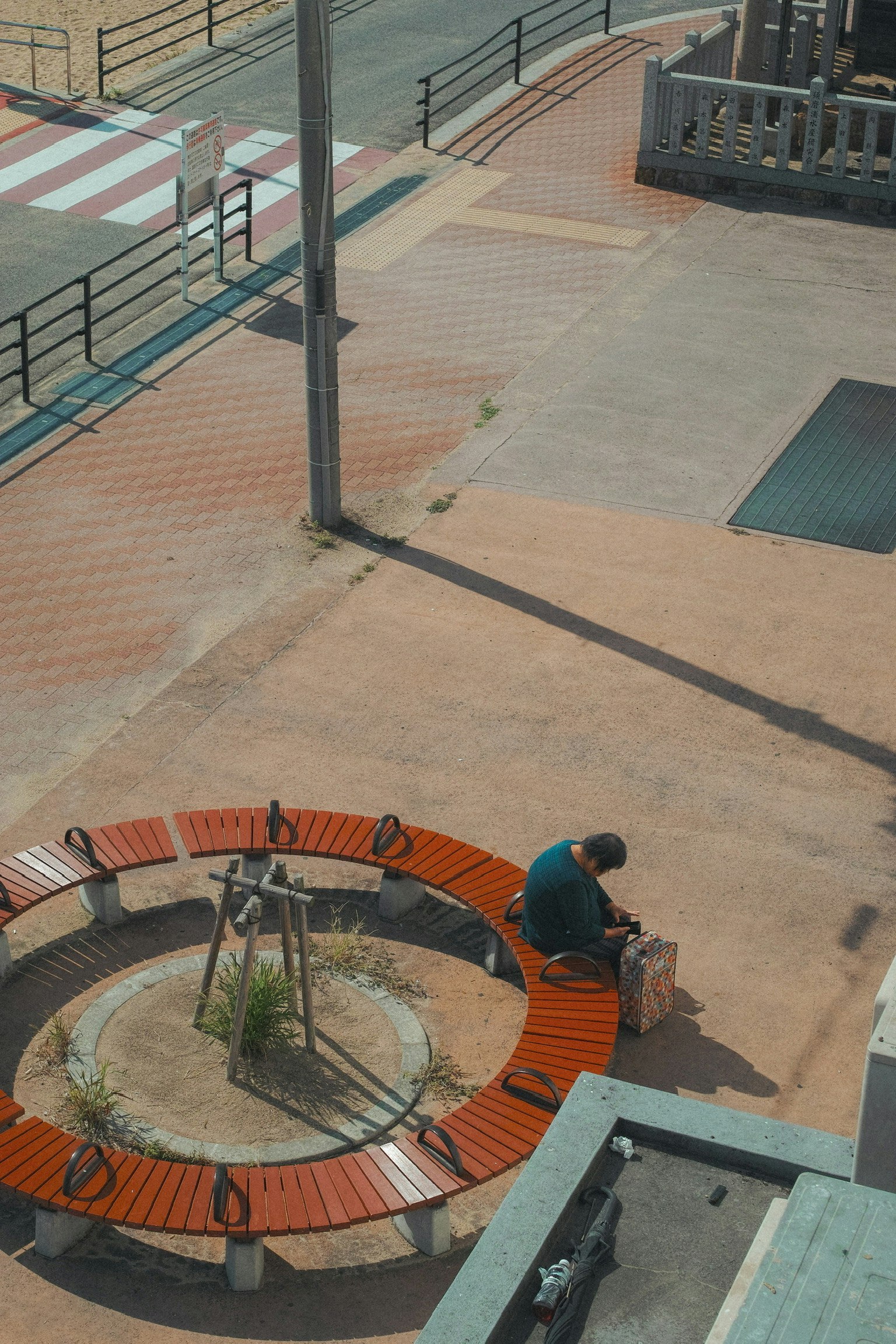 公園の円形ベンチに座る人と周囲の舗装された道