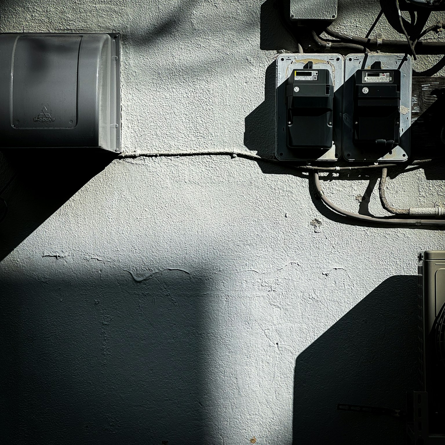 Contadores eléctricos montados en una pared blanca con sombras contrastantes