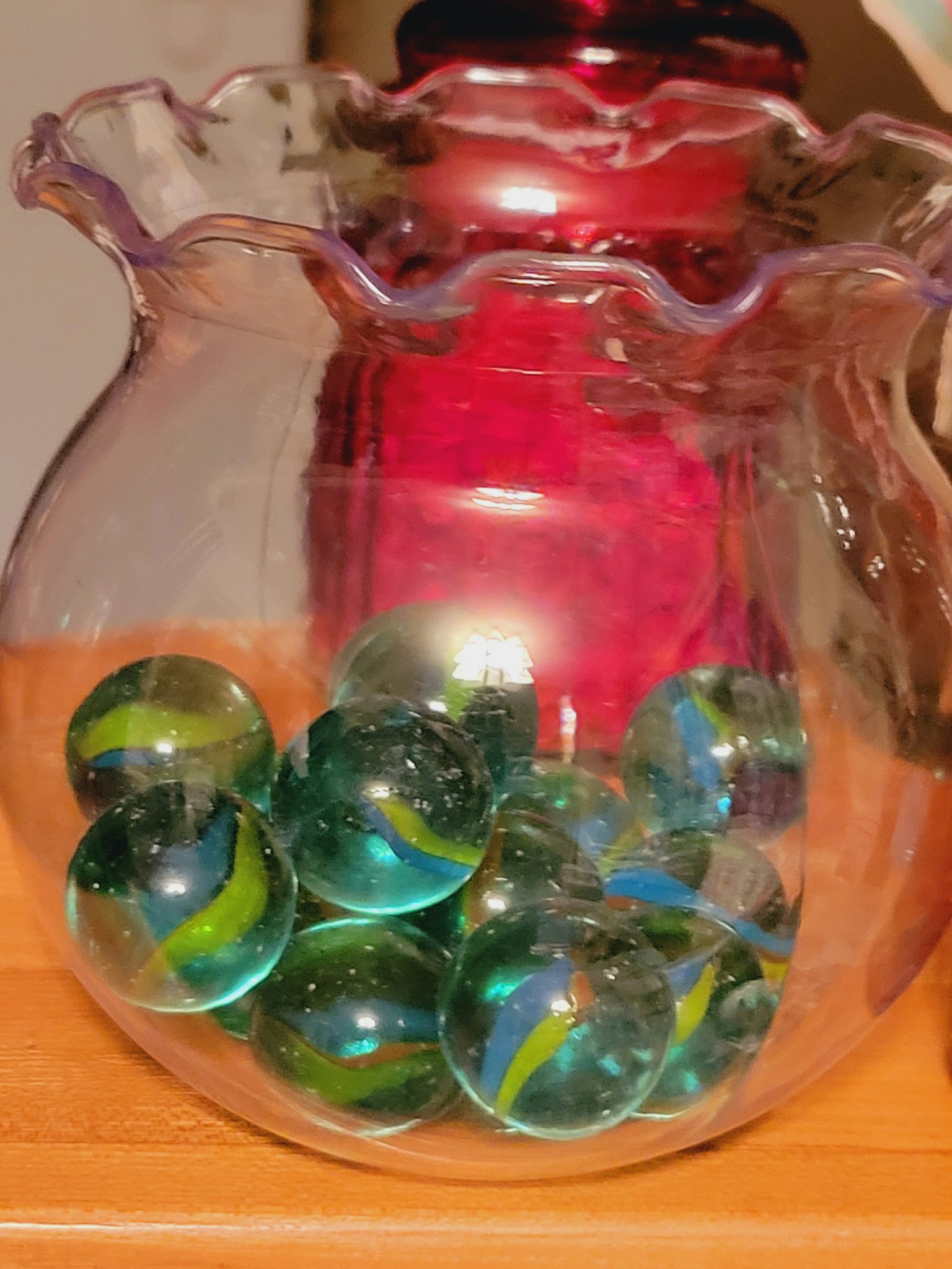 Colorful marbles in a clear glass vase with a ruffled edge