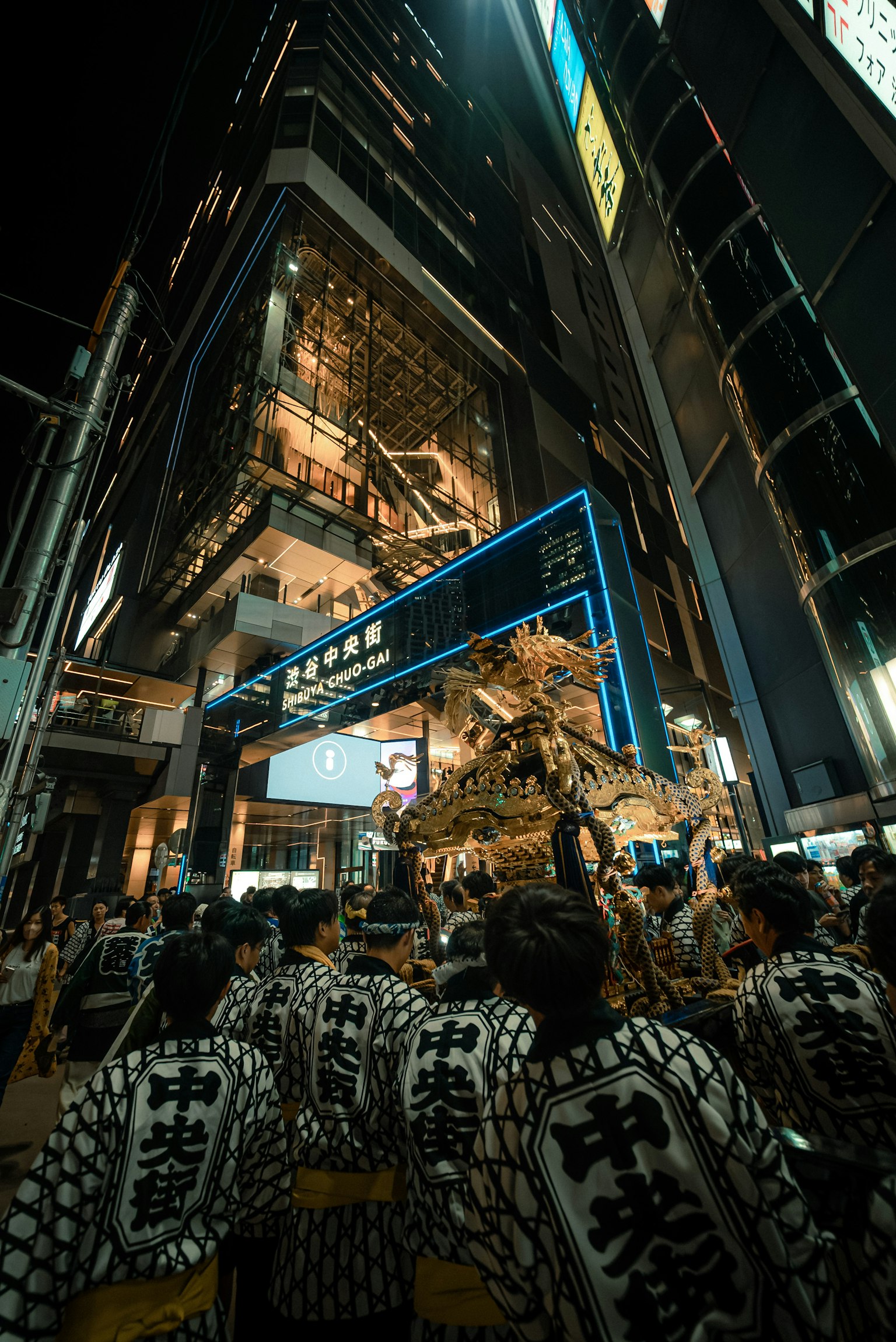 夜晚城市中聚集的人们参加节日 明亮的建筑灯光下穿着传统服装