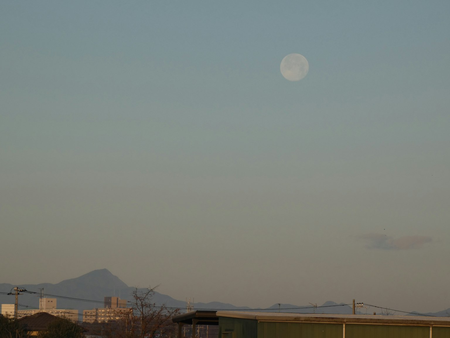 Luna grande in un cielo sereno con montagne lontane
