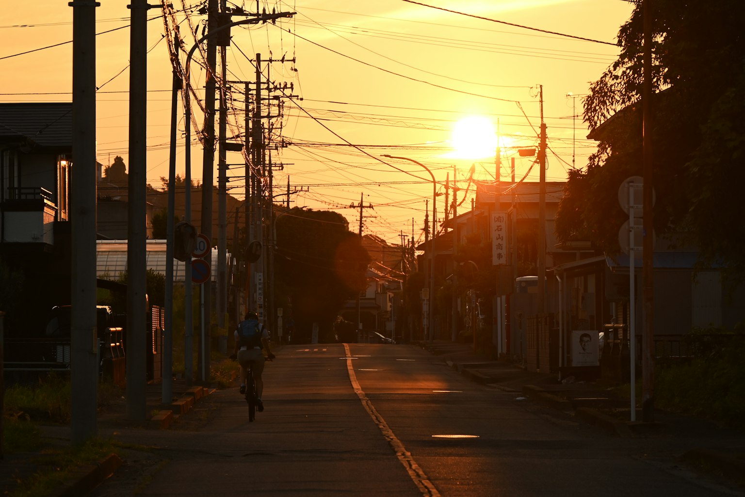 Ein Radfahrer fährt auf einer leeren Straße mit Sonnenuntergang im Hintergrund
