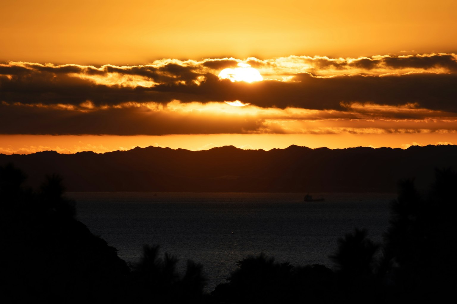 Hermoso atardecer con el sol saliendo entre nubes siluetas del mar y las montañas