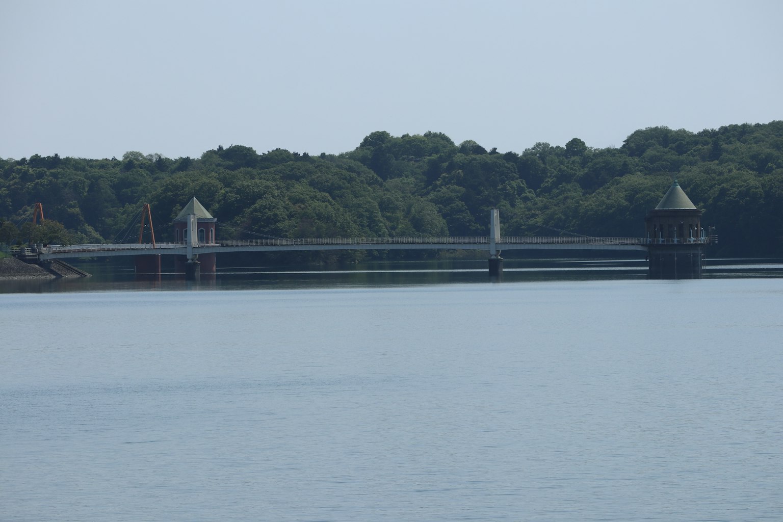 Eine Brücke über einen ruhigen See umgeben von üppigem Grün
