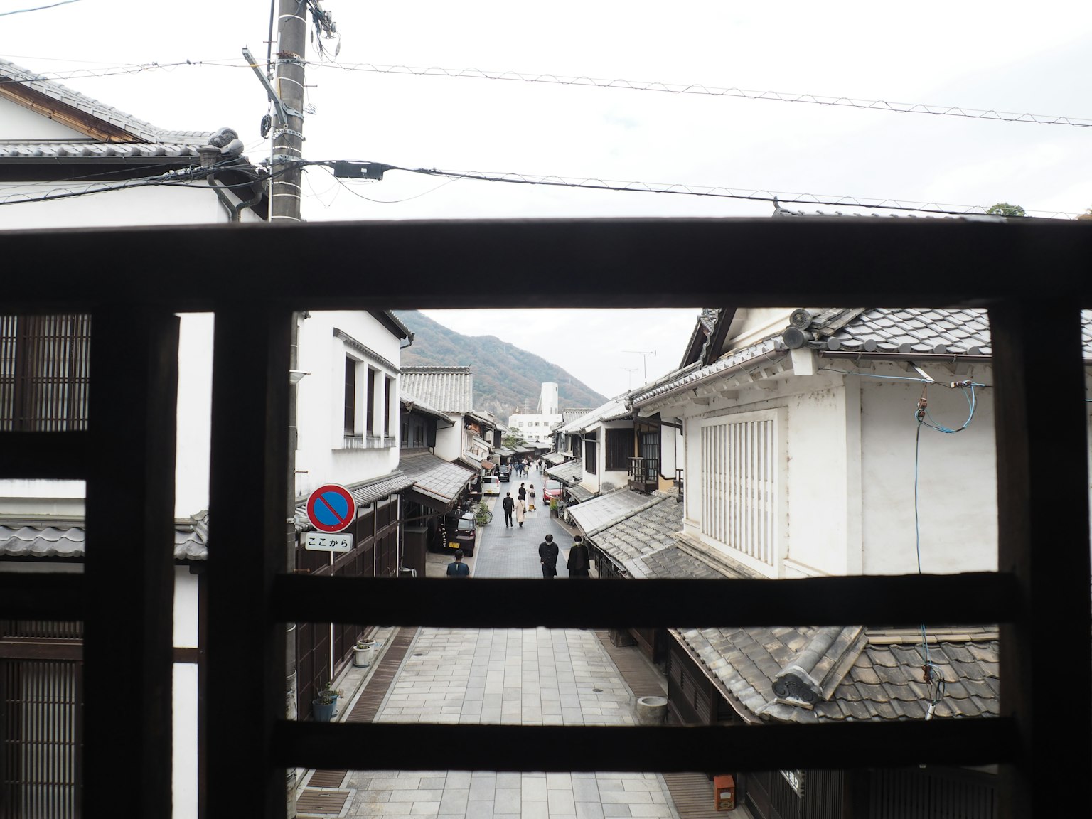 Pemandangan melalui jendela yang menunjukkan jalan kota tua dengan suasana tenang setelah hujan