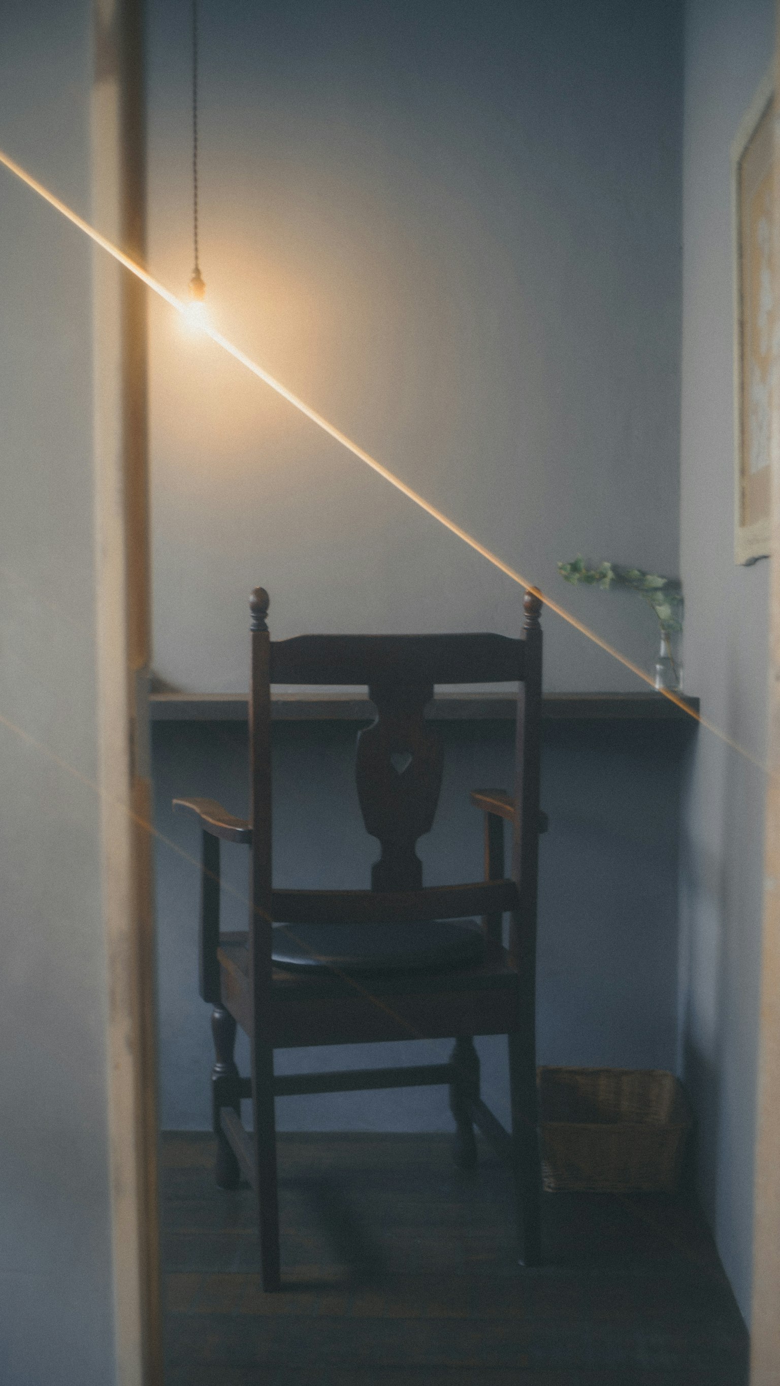 青い壁の部屋に置かれた木製の椅子とテーブル 照明が斜めに当たるシンプルなインテリア