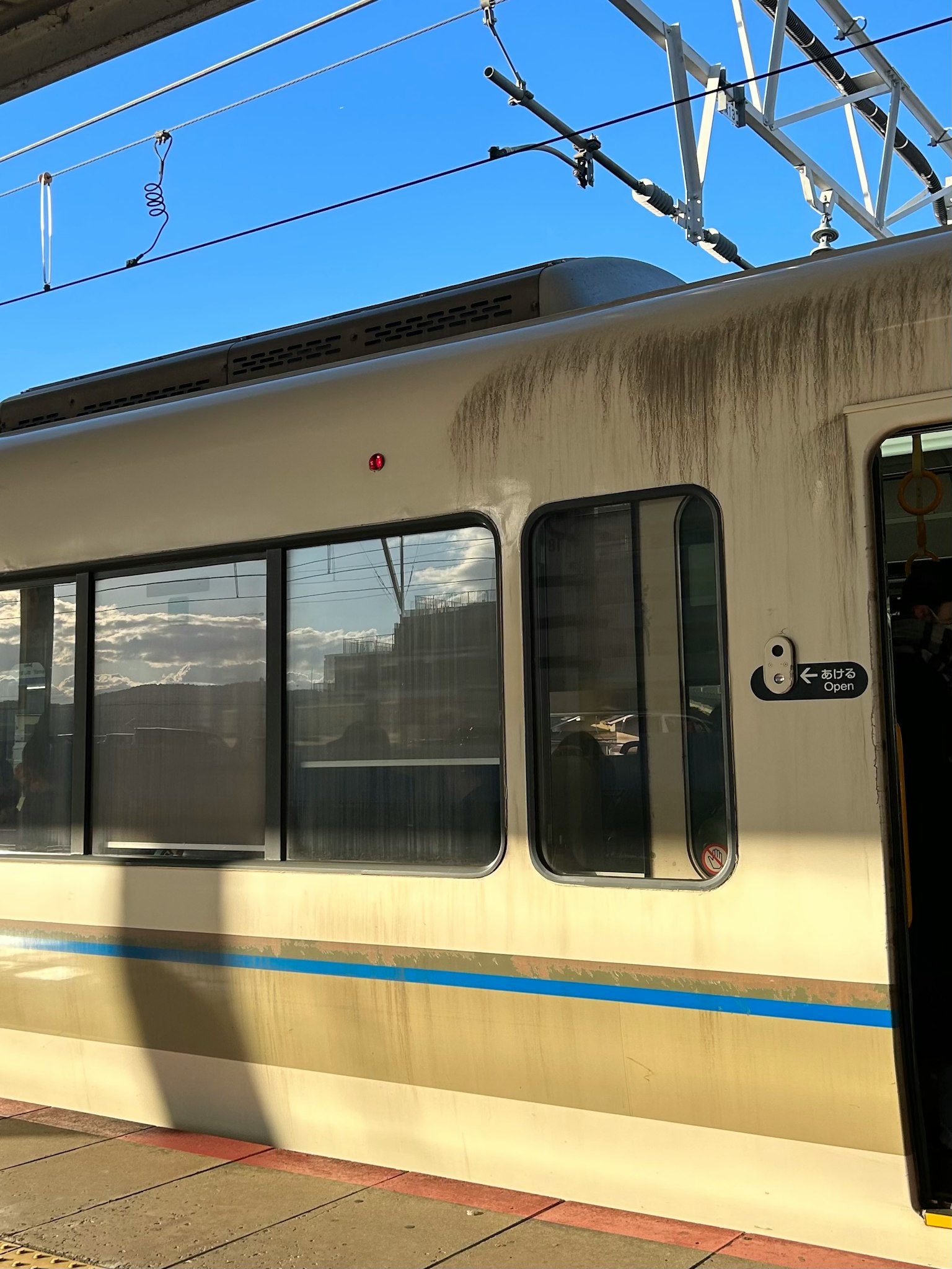 Un lato di treno sporco con finestre sotto un cielo blu