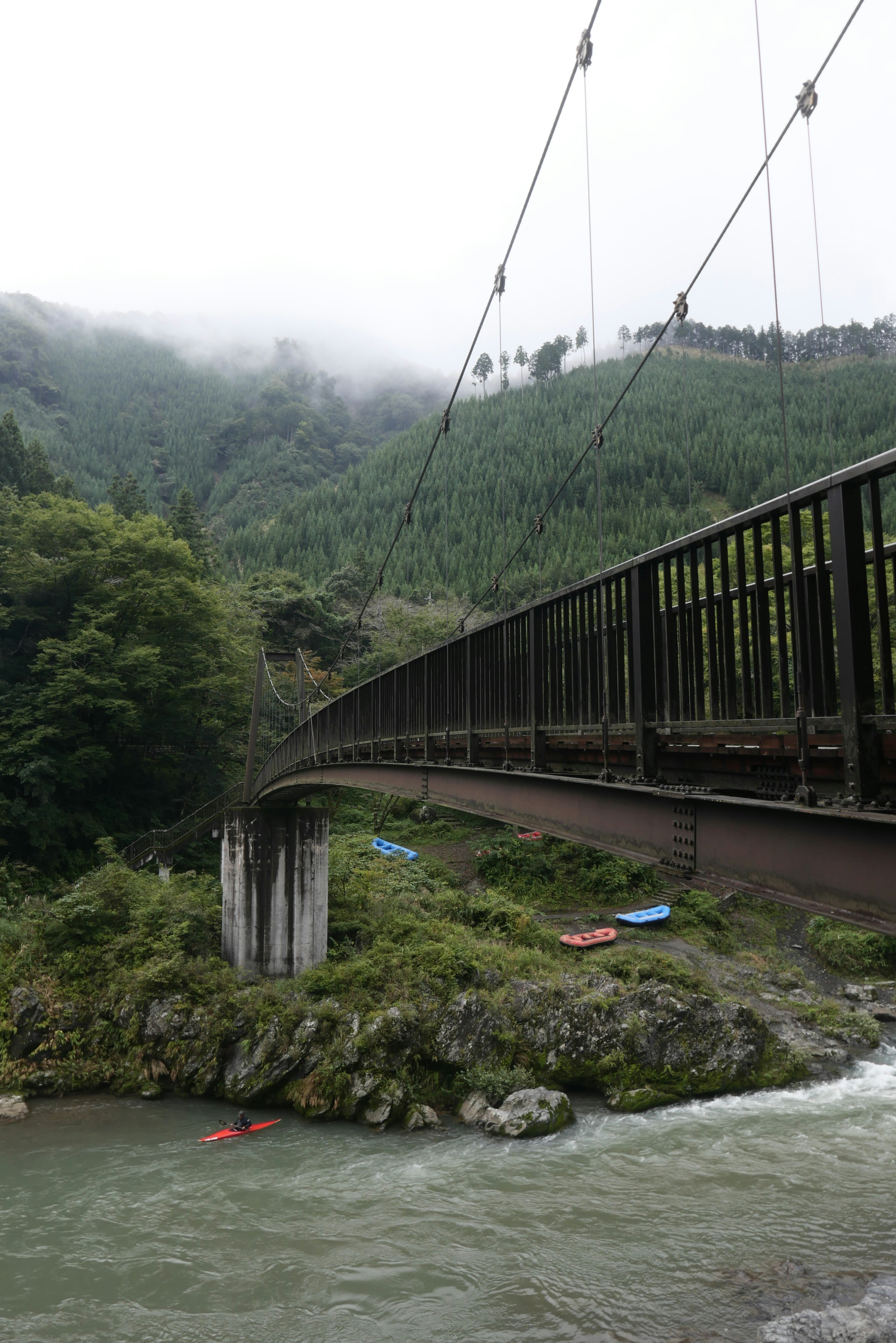 霧の山あいを渡る吊り橋のある渓谷の風景