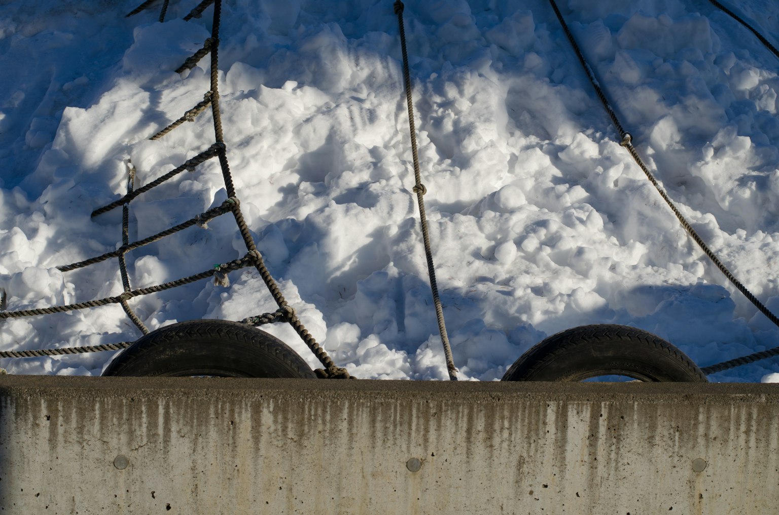 Un mur en béton avec des pneus noirs et un arrière-plan de neige