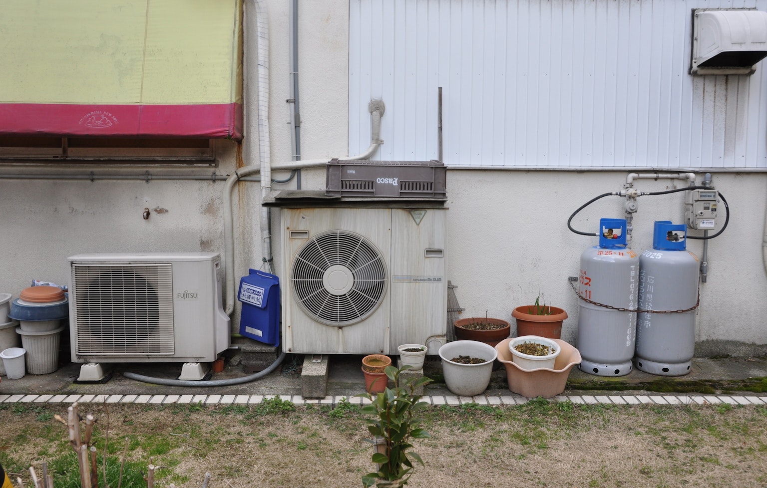 Unità di climatizzazione e bombole di gas accanto a un muro di edificio