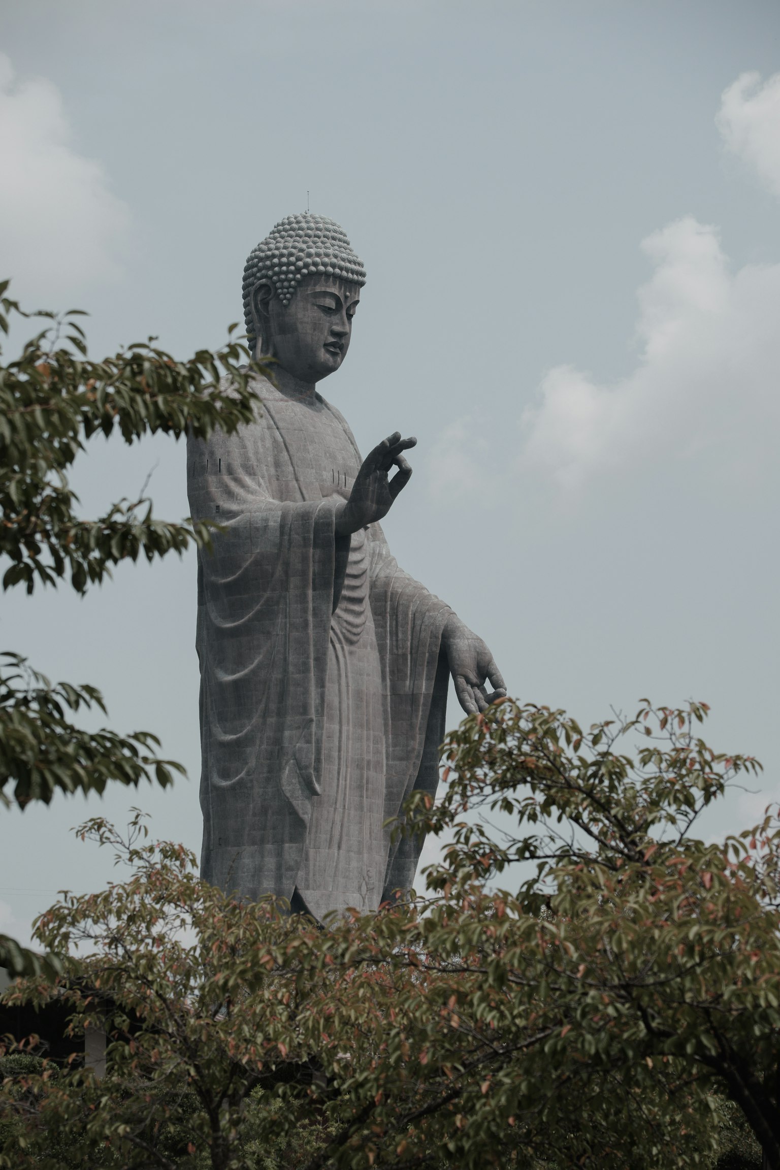 Tall Buddha statue surrounded by trees in a serene landscape