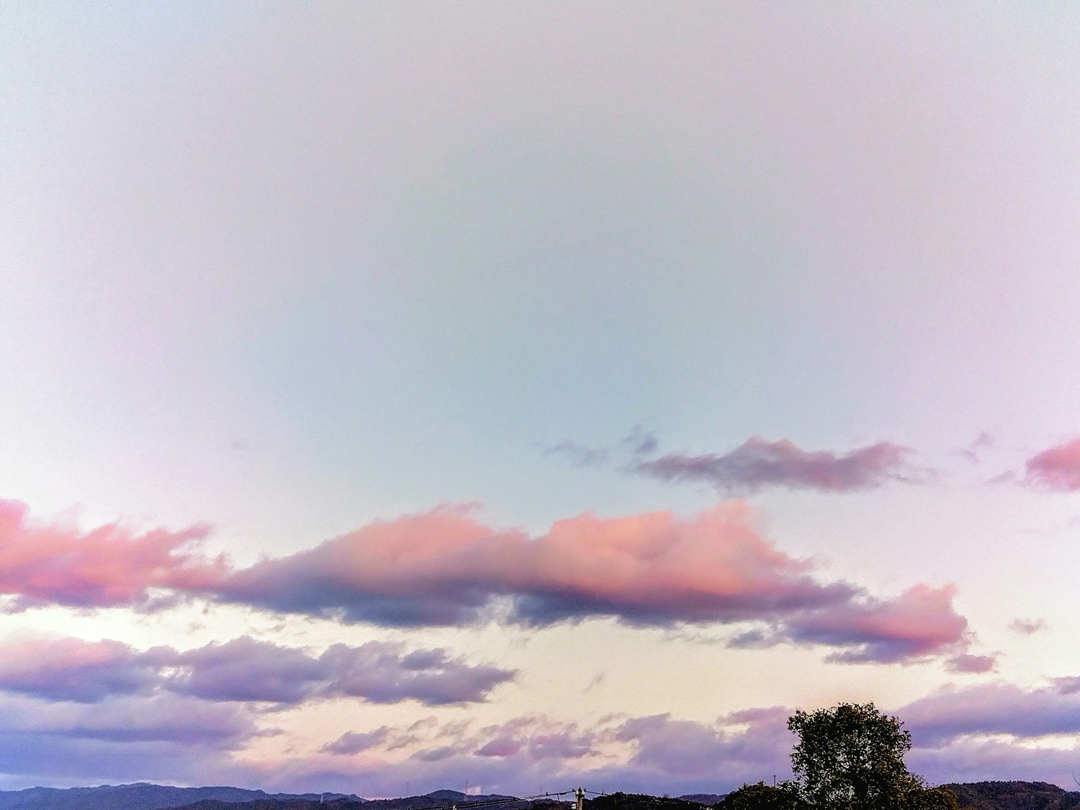 穏やかな夕焼けの空にピンク色の雲が浮かぶ風景