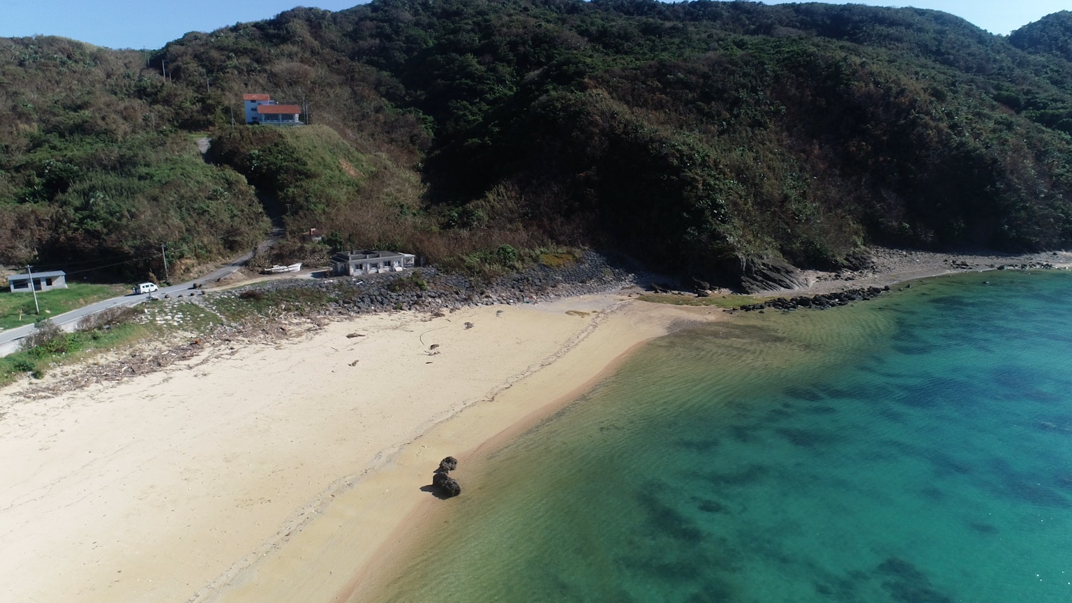 มุมมองทางอากาศของชายหาดที่สวยงามพร้อมน้ำทะเลสีฟ้าสดใสและภูเขาสีเขียวชอุ่มในพื้นหลัง