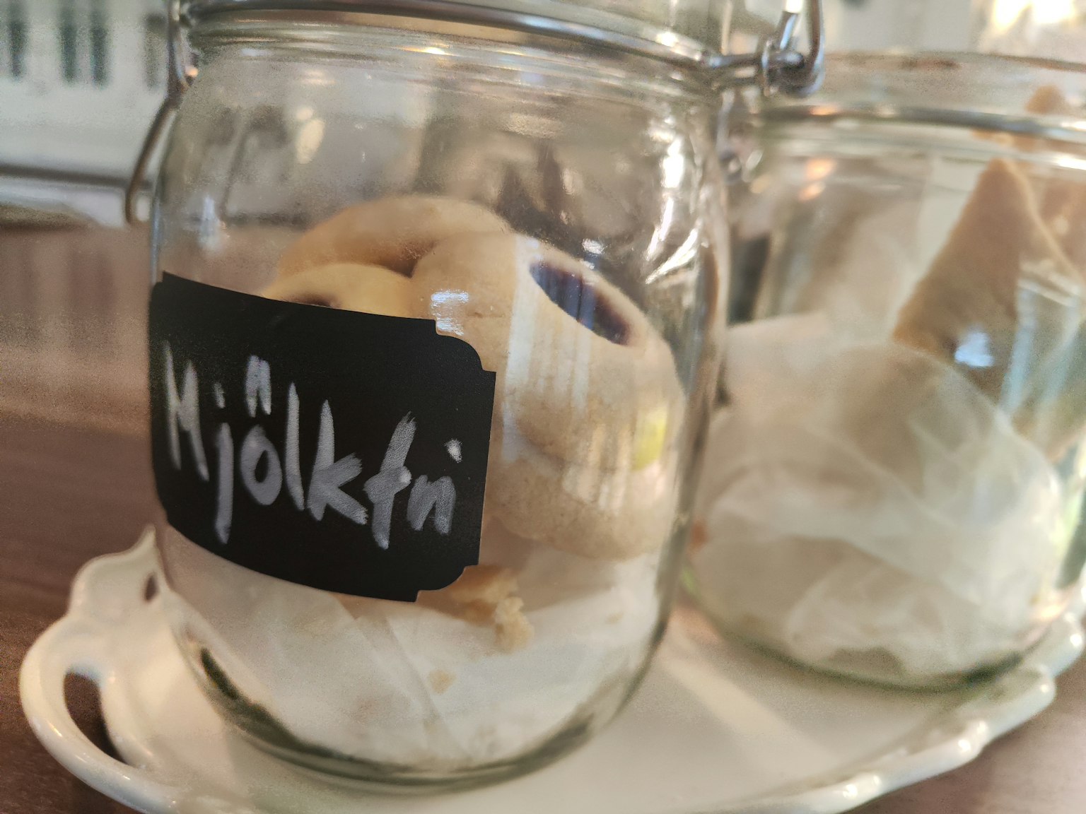 ขวดแก้วที่บรรจุขนมอบพร้อมป้ายสีดำเขียนว่า 'Mjölkfrü'