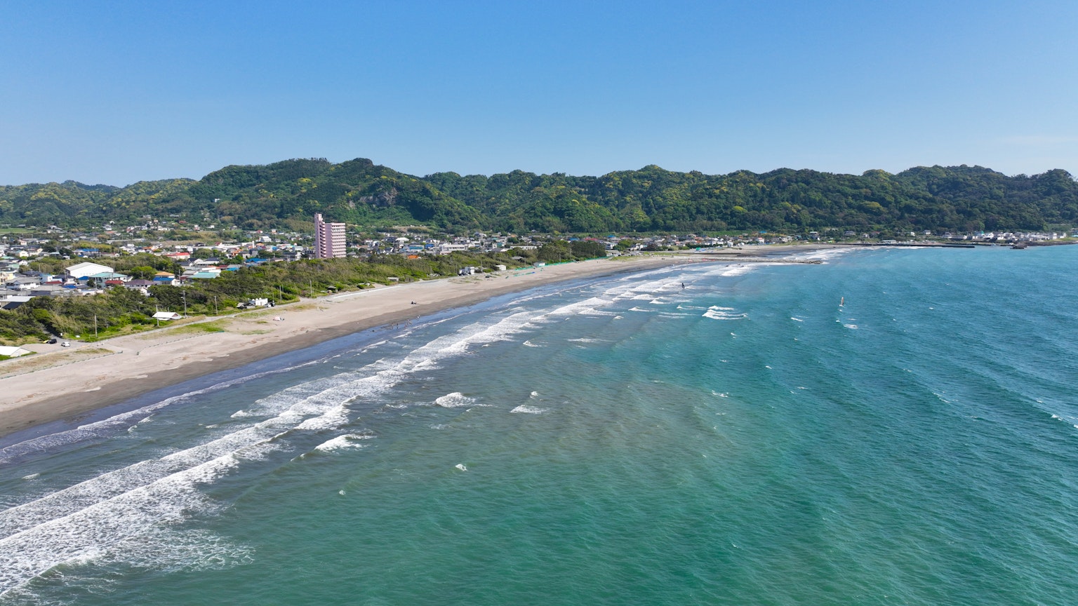 ชายหาดที่สวยงามพร้อมน้ำทะเลสีฟ้าสดใสและภูเขาล้อมรอบเมืองชายฝั่ง
