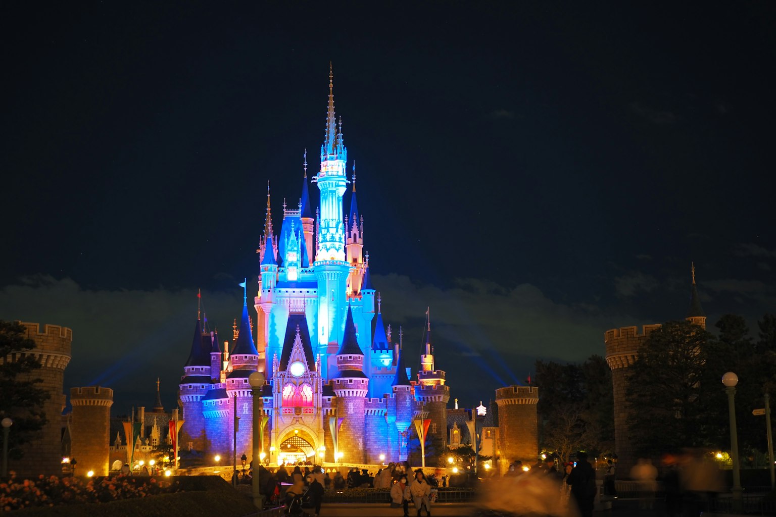 Castillo de Disney iluminado en azul y naranja por la noche