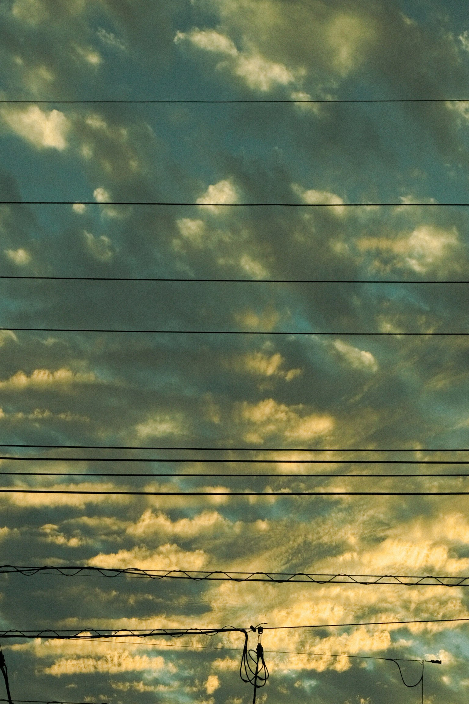 Himmel mit blauen und gelben Wolken und Stromleitungen
