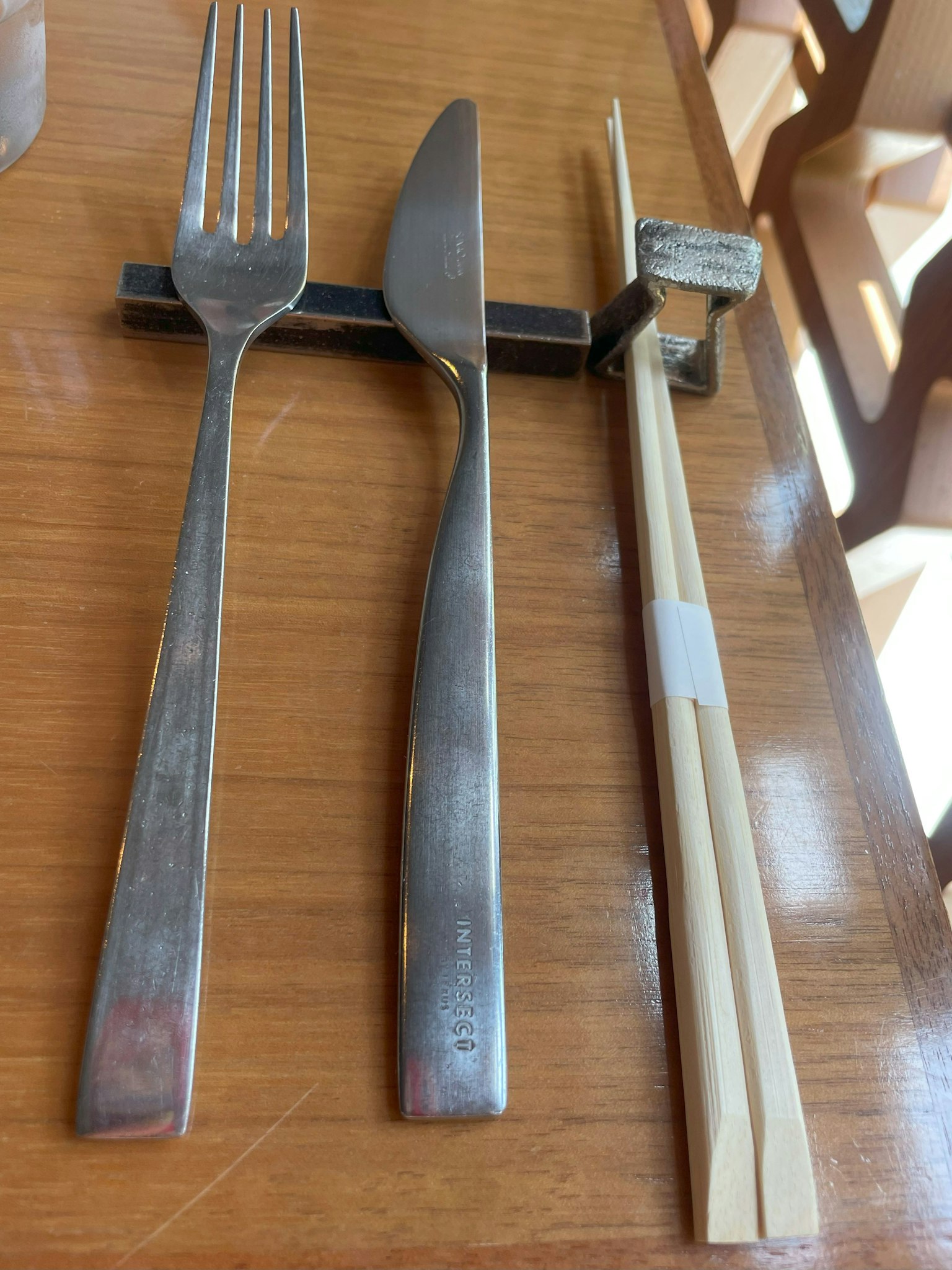 Tenedor cuchillo y palillos dispuestos sobre una mesa de madera