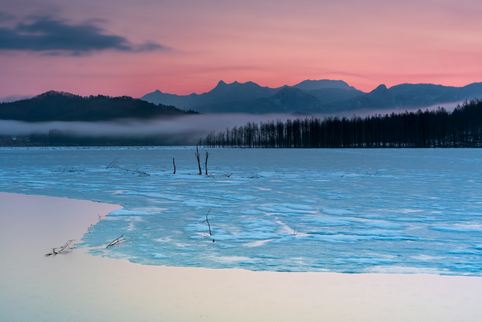 Frozen lake landscape with mountains and colorful twilight sky