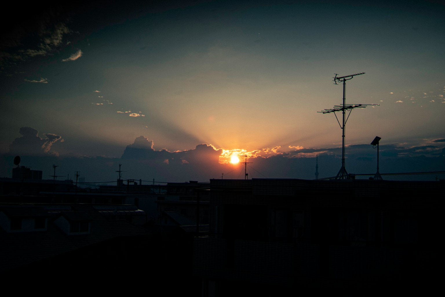 夕日が雲の間から差し込む美しい景色と屋上のアンテナ