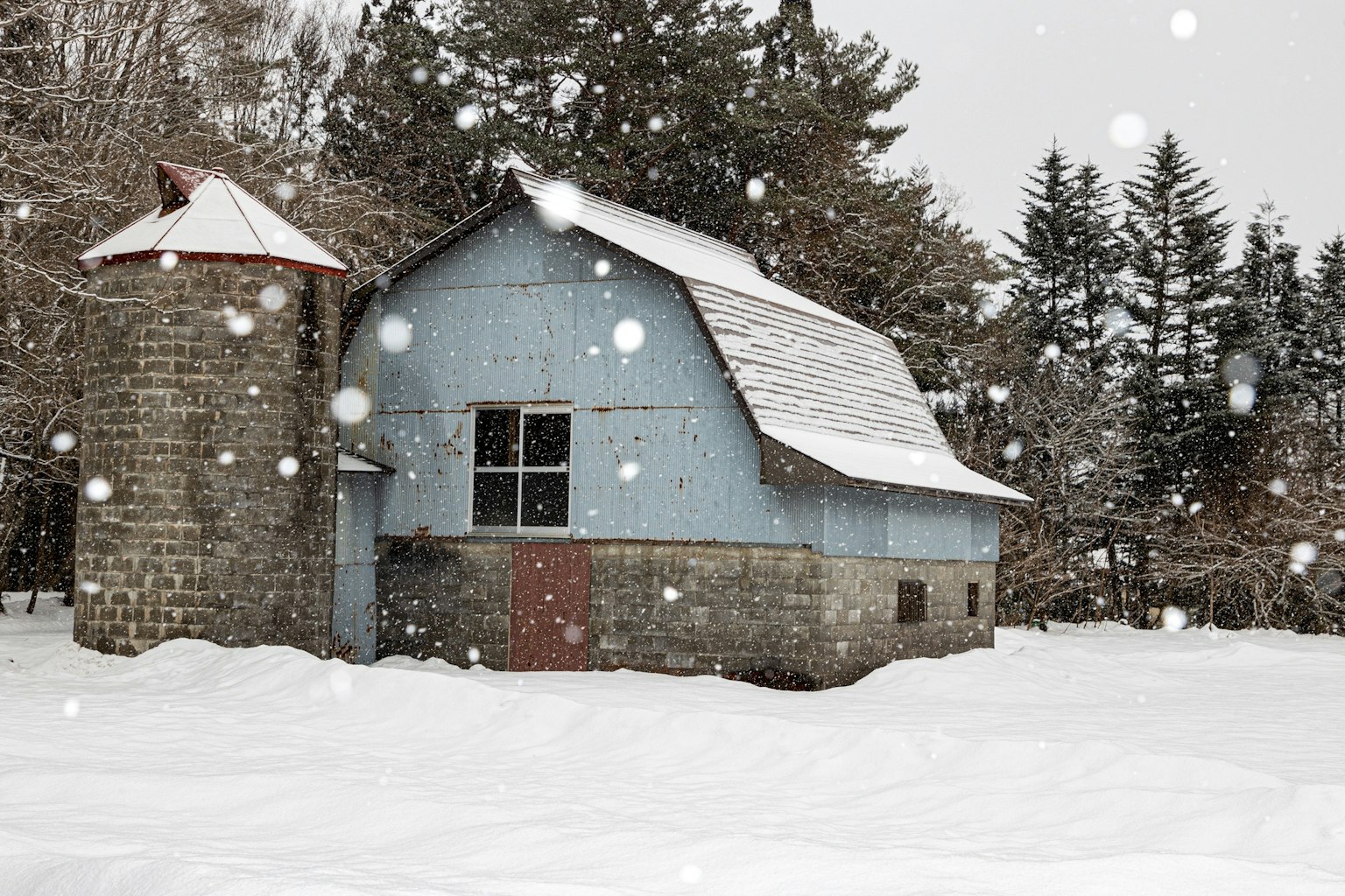 雪中藍色穀倉和石塔