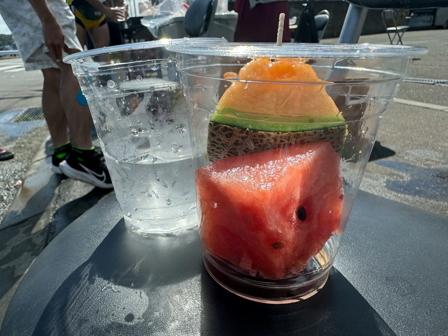 Coppa di frutta con pezzi di anguria e melone accanto a un bicchiere d'acqua