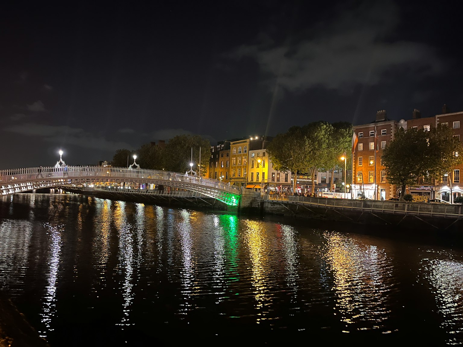 Pemandangan malam Dublin dengan Jembatan Ha'penny dan pantulan di Sungai Liffey