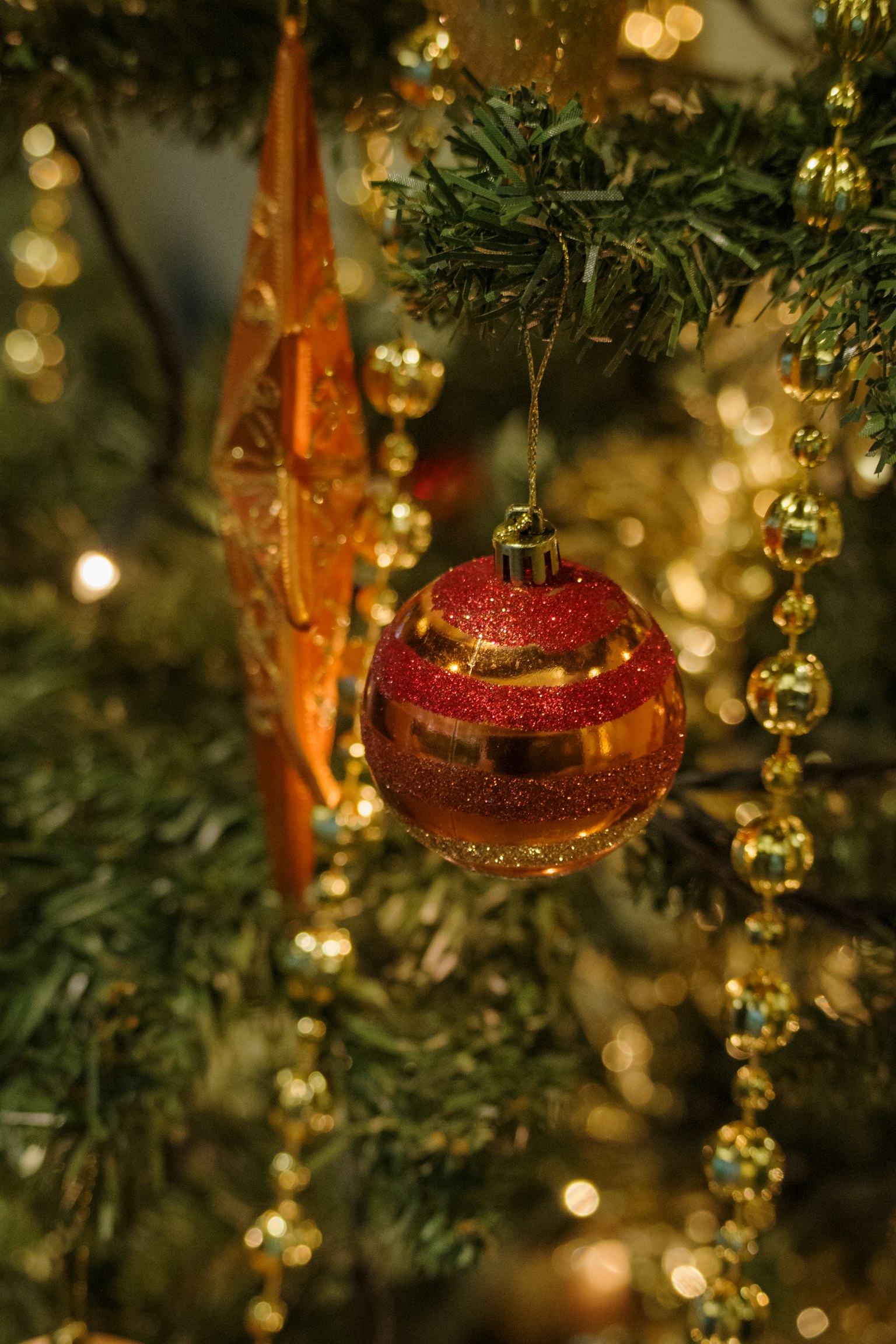 Trang trí màu đỏ và vàng treo trên cây thông Noel với hạt vàng